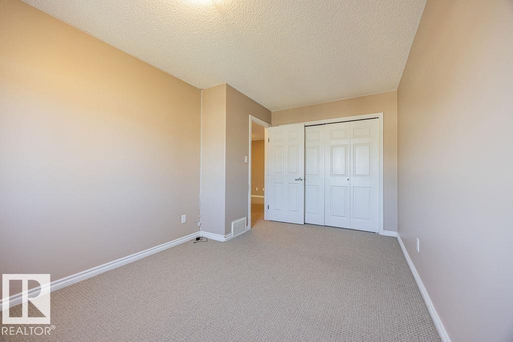 Neutral-toned room featuring light beige carpeting, white baseboards, and a textured ceiling - 14 9350 211 Street, Edmonton, AB - Indoor Photo Showing Other Room