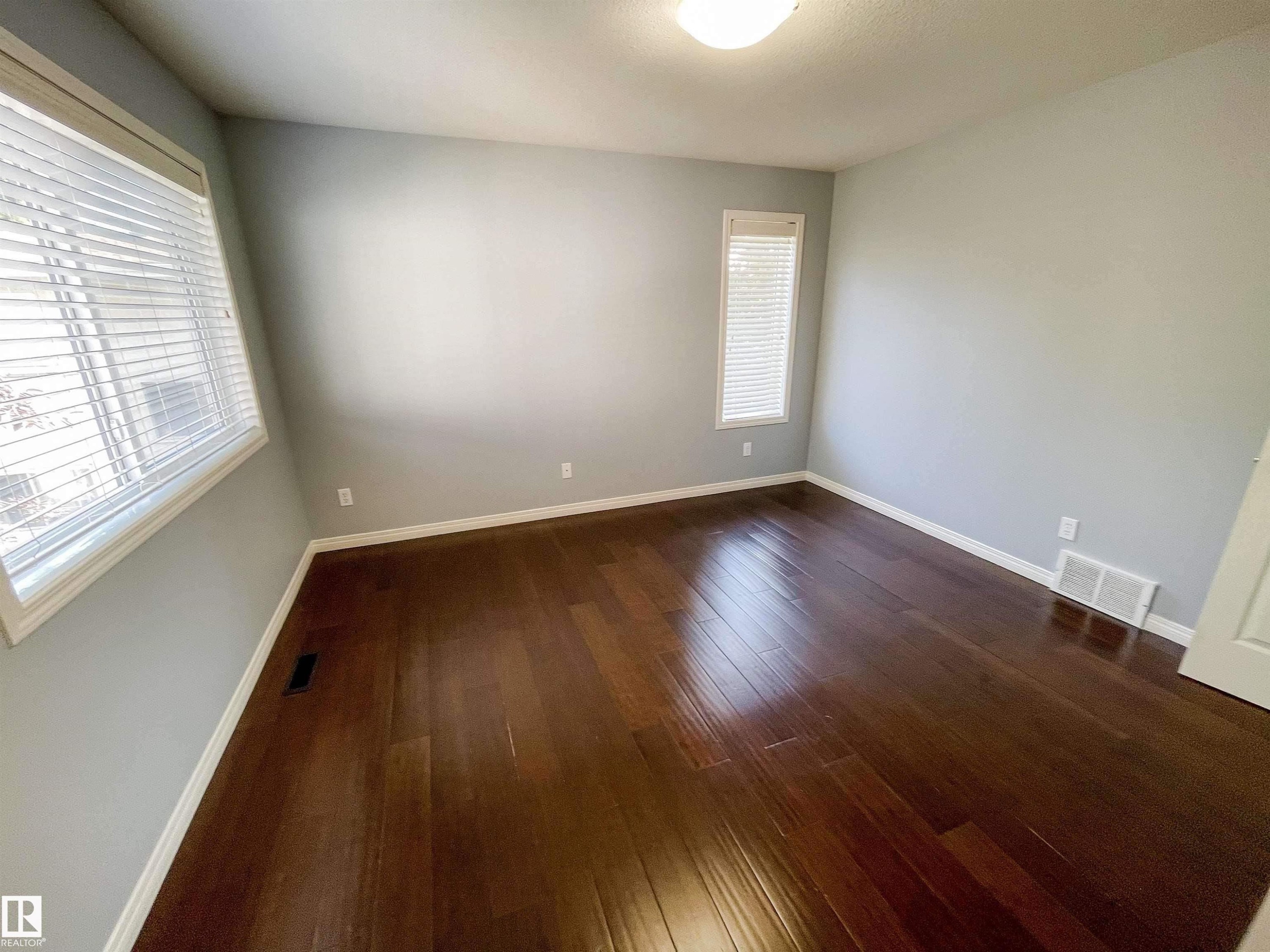 Spacious room featuring rich wood-finish flooring, light gray wall paint, and white trim - 5806 118 Avenue Nw, Edmonton, AB - Indoor Photo Showing Other Room