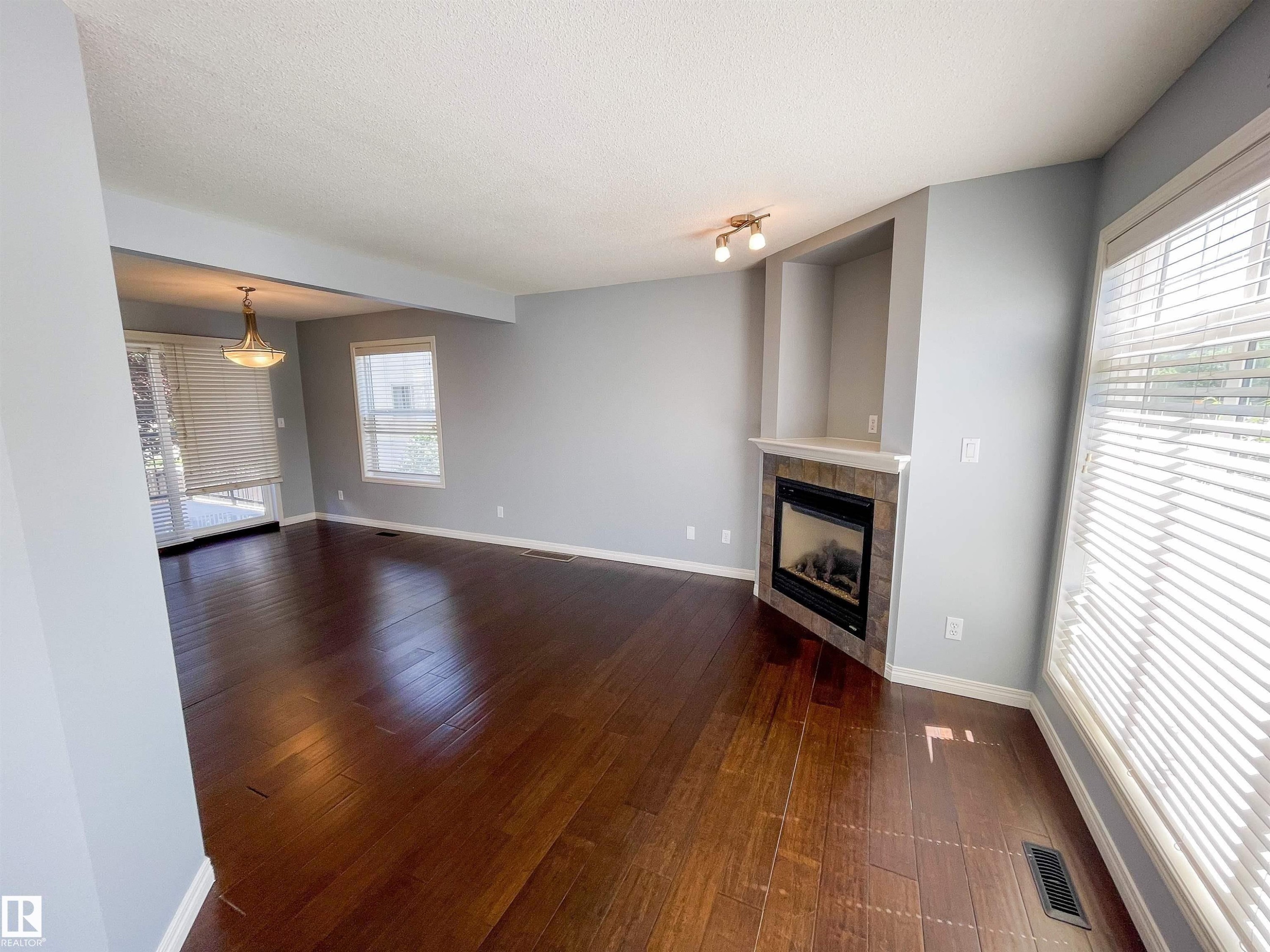 Spacious interior featuring wood-finish flooring, a built-in fireplace with a stone-finish surround, and an integrated display niche - 5806 118 Avenue Nw, Edmonton, AB - Indoor Photo Showing Living Room With Fireplace