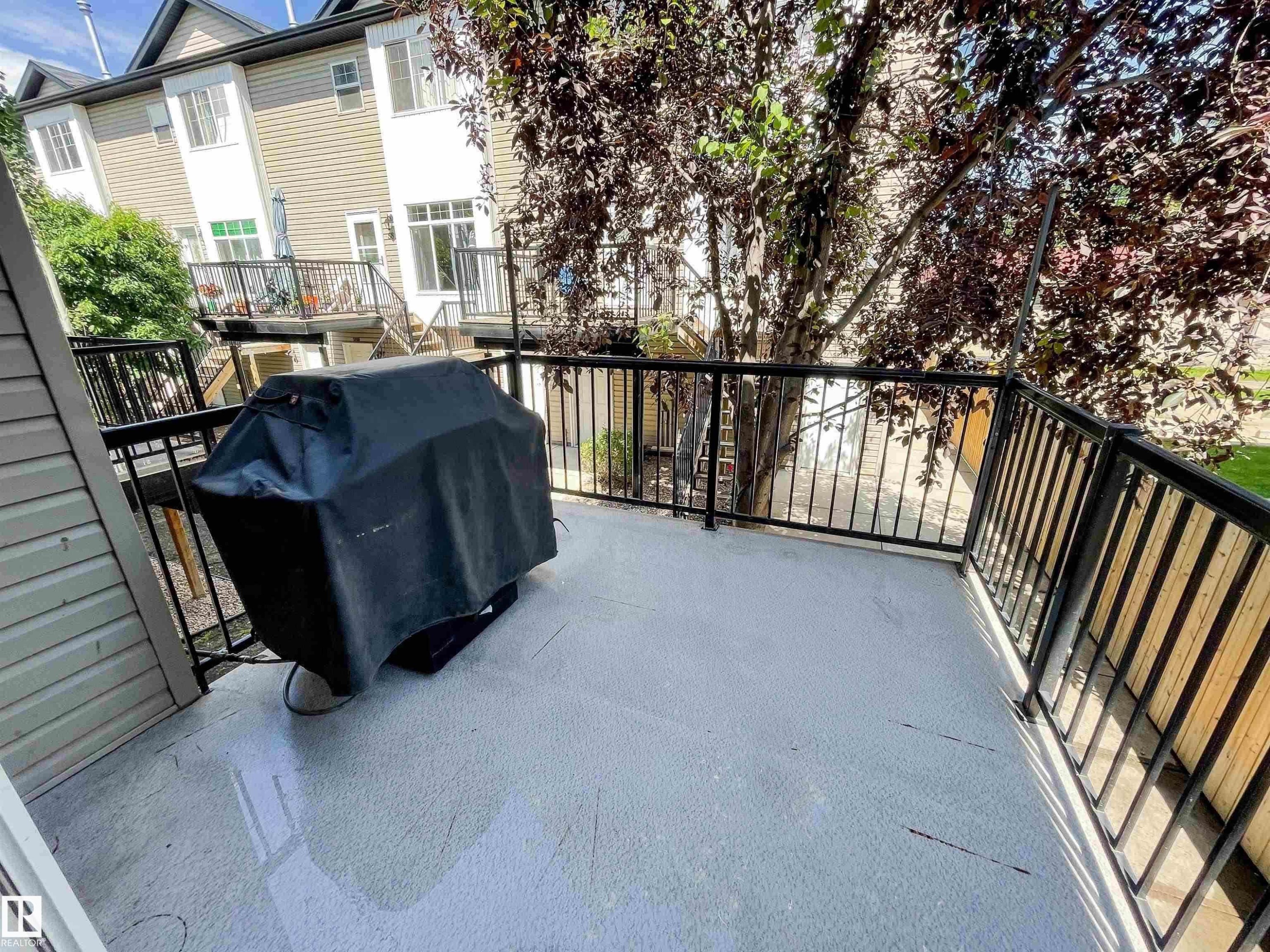 Private balcony featuring a light-colored surface, black metal railings, and mature tree coverage - 5806 118 Avenue Nw, Edmonton, AB - Outdoor With Exterior