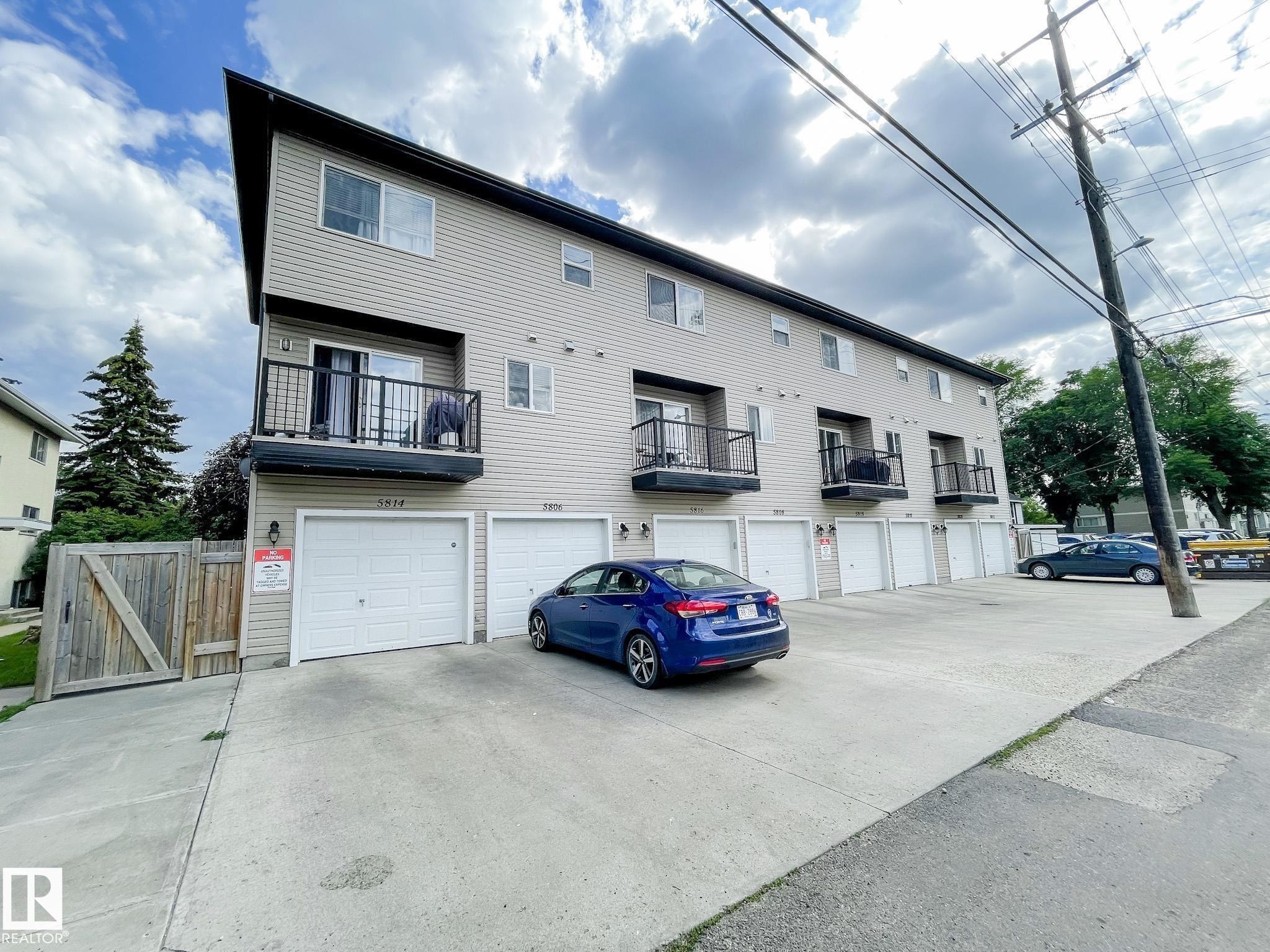 Multi-level residential building featuring light-colored siding and a contrasting dark fascia - 5806 118 Avenue Nw, Edmonton, AB - Outdoor
