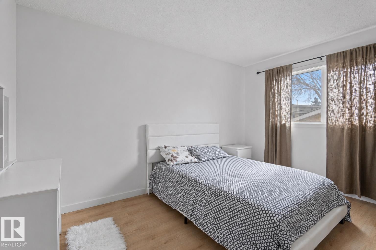 Bedroom featuring wood-finish flooring, a white-framed window, and white painted walls - 1566 Lakewood Road Nw, Edmonton, AB - Indoor Photo Showing Bedroom