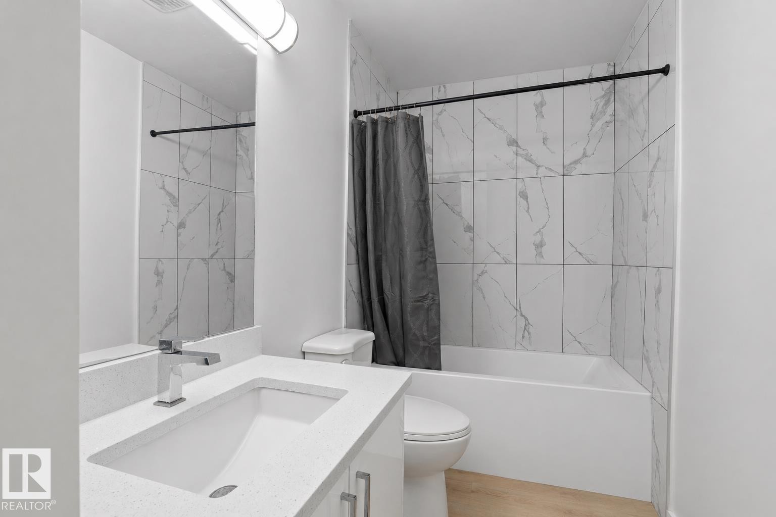 Bathroom featuring a white vanity with integrated sink, chrome faucet, and spacious mirror - 1566 Lakewood Road Nw, Edmonton, AB - Indoor Photo Showing Bathroom