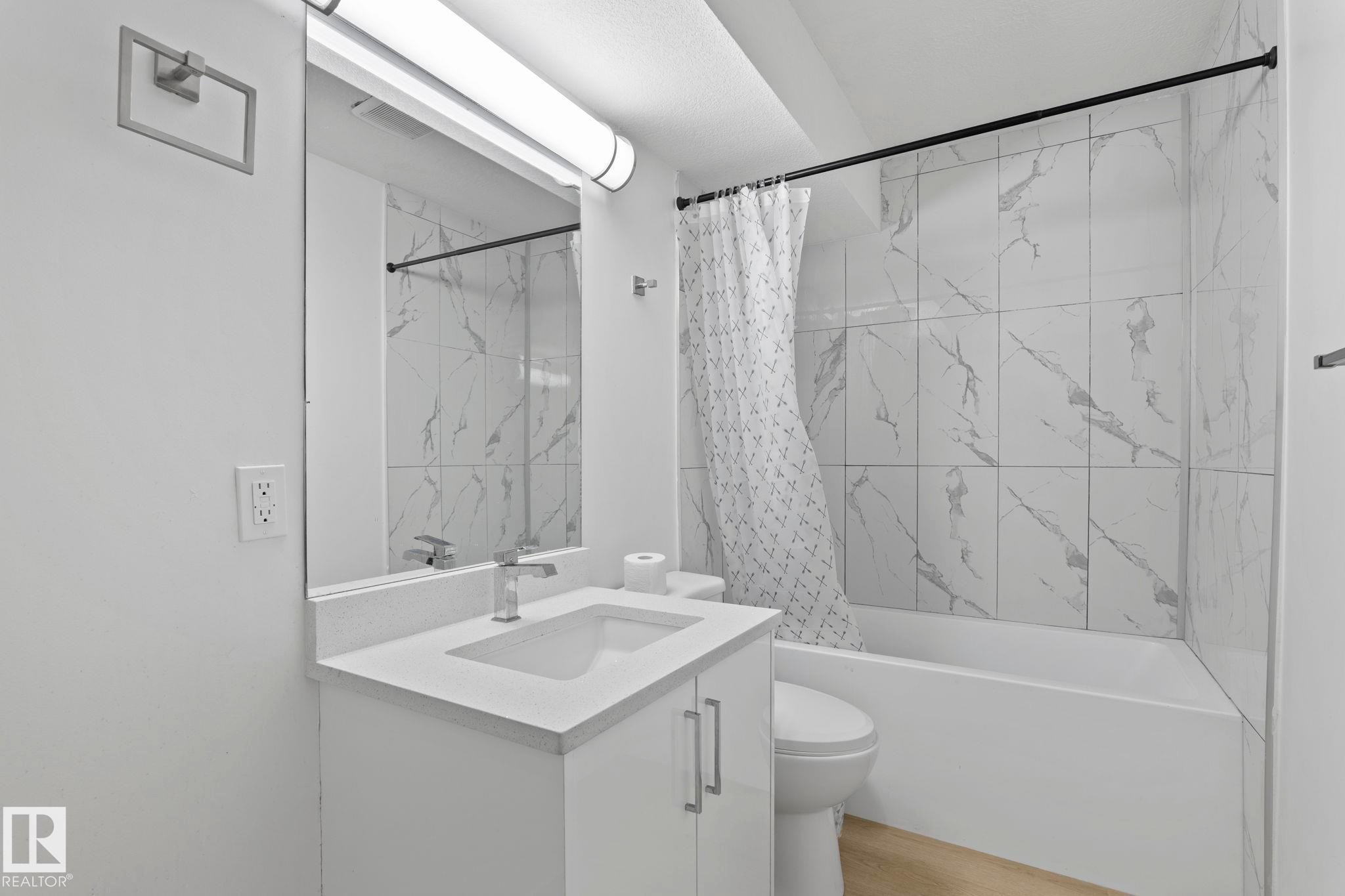 Bathroom featuring a white vanity with an integrated sink, polished chrome faucet, and a large rectangular mirror - 1566 Lakewood Road Nw, Edmonton, AB - Indoor Photo Showing Bathroom
