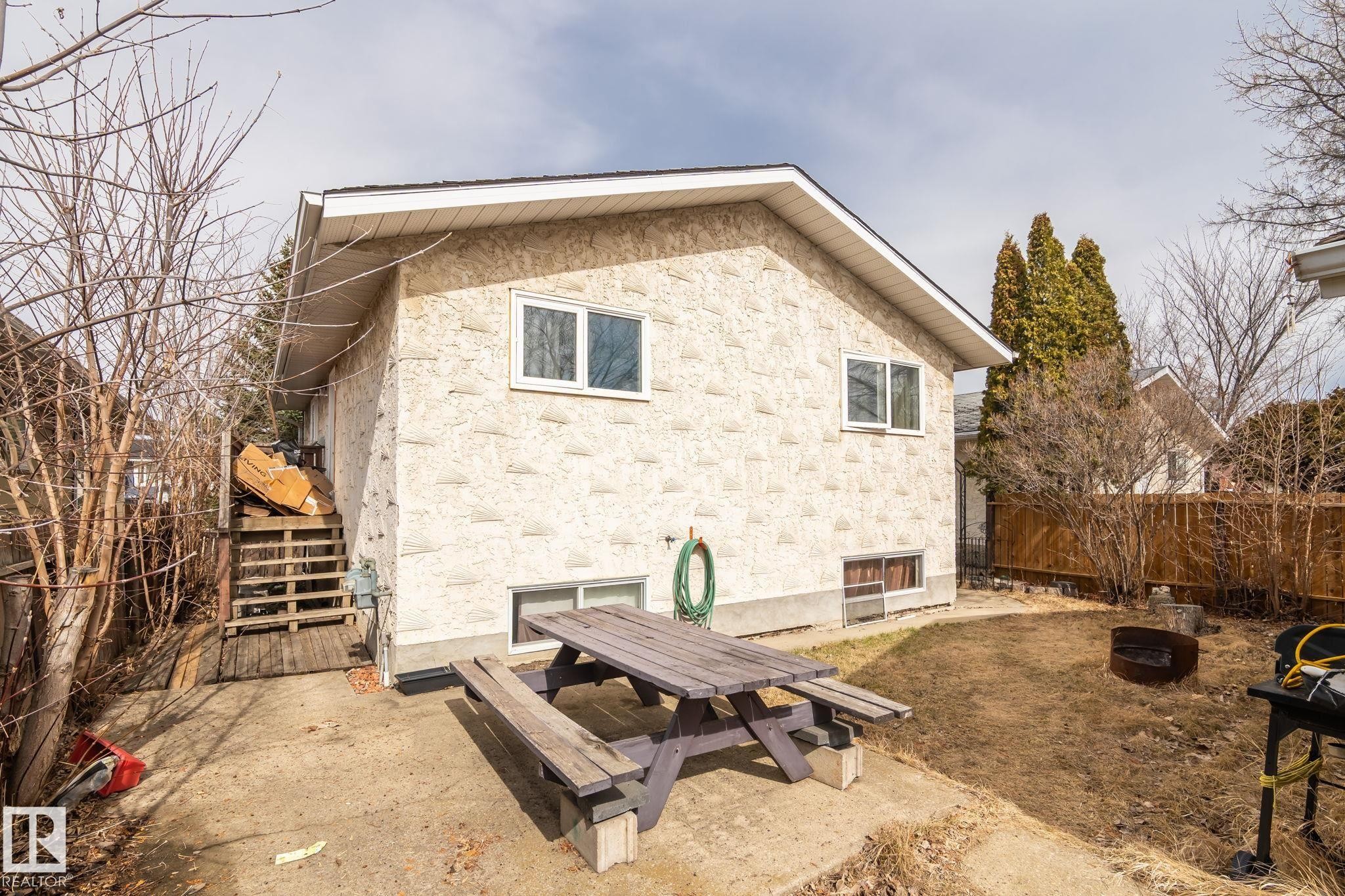 Rear exterior of the property featuring textured stucco siding and a gable roofline - 1566 Lakewood Road Nw, Edmonton, AB - Outdoor