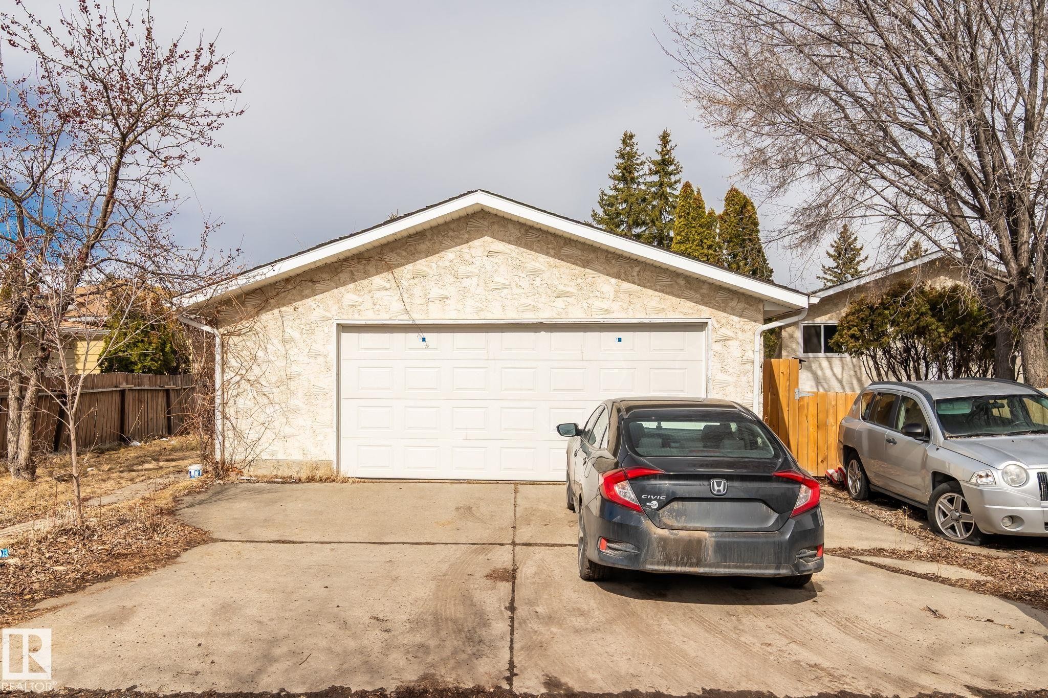 Detached two-car garage featuring a white panel door and concrete driveway - 1566 Lakewood Road Nw, Edmonton, AB - Outdoor With Exterior