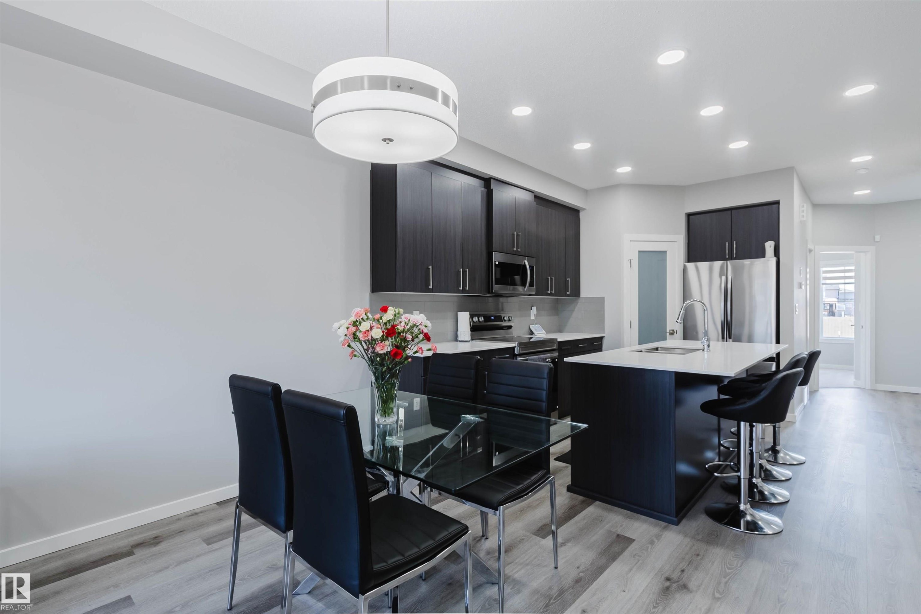 Modern kitchen featuring dark wood-finish cabinetry, stainless steel appliances, and a central island with countertop seating - 343 Edgemont Drive, Edmonton, AB - Indoor