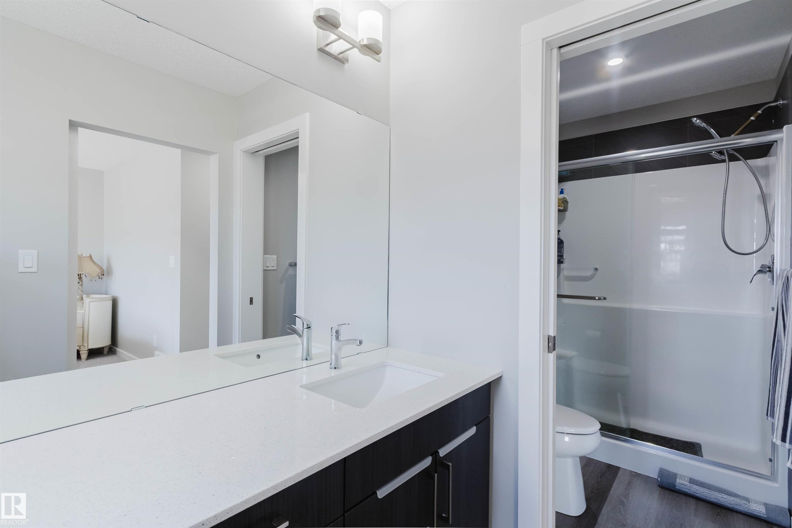 Bathroom vanity featuring a white countertop, undermount sink, and dark wood-finish cabinetry with silver hardware - 343 Edgemont Drive, Edmonton, AB - Indoor Photo Showing Bathroom