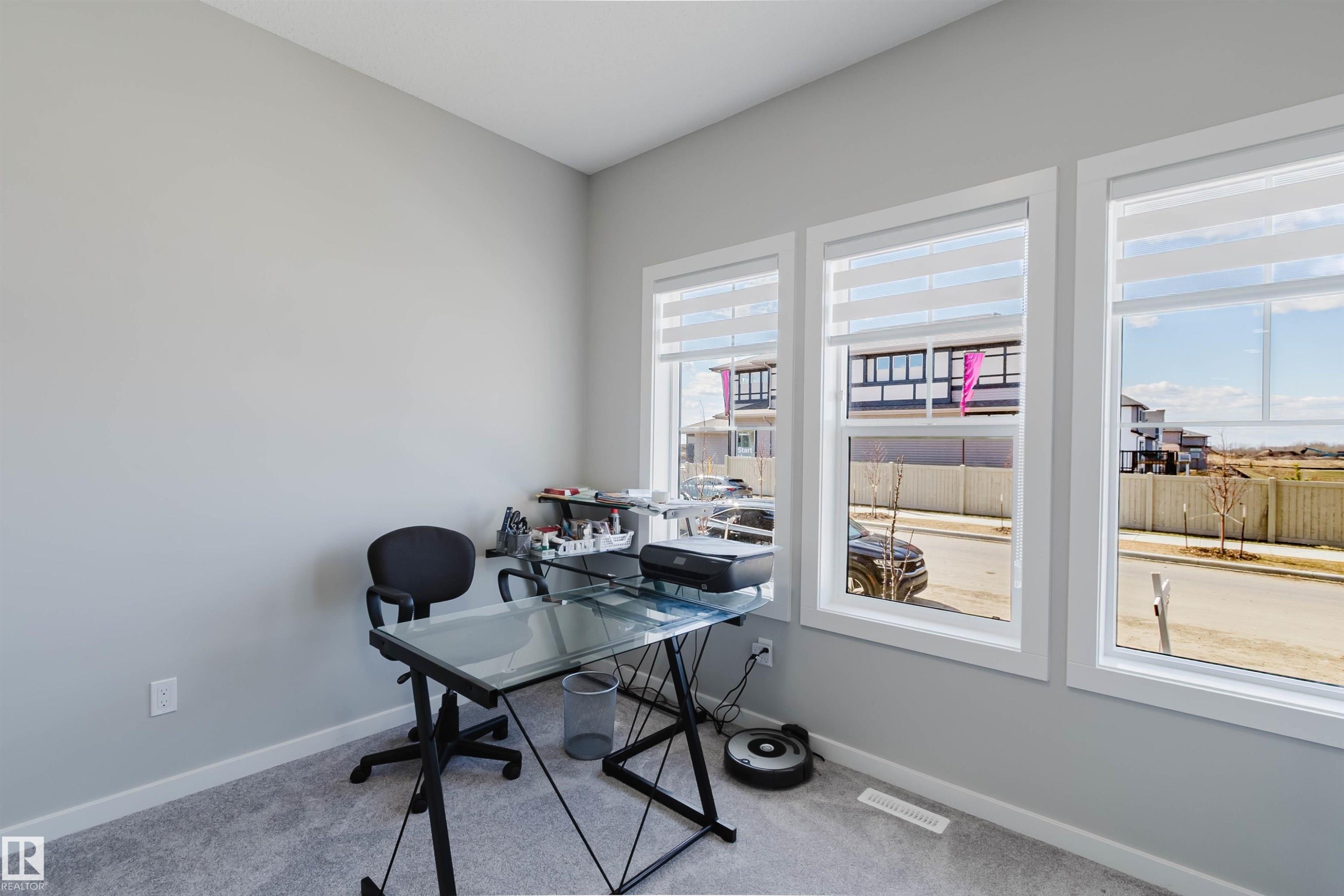 Bright interior space featuring three large windows with white trim, light gray painted walls, and gray carpeting - 343 Edgemont Drive, Edmonton, AB - Indoor Photo Showing Office