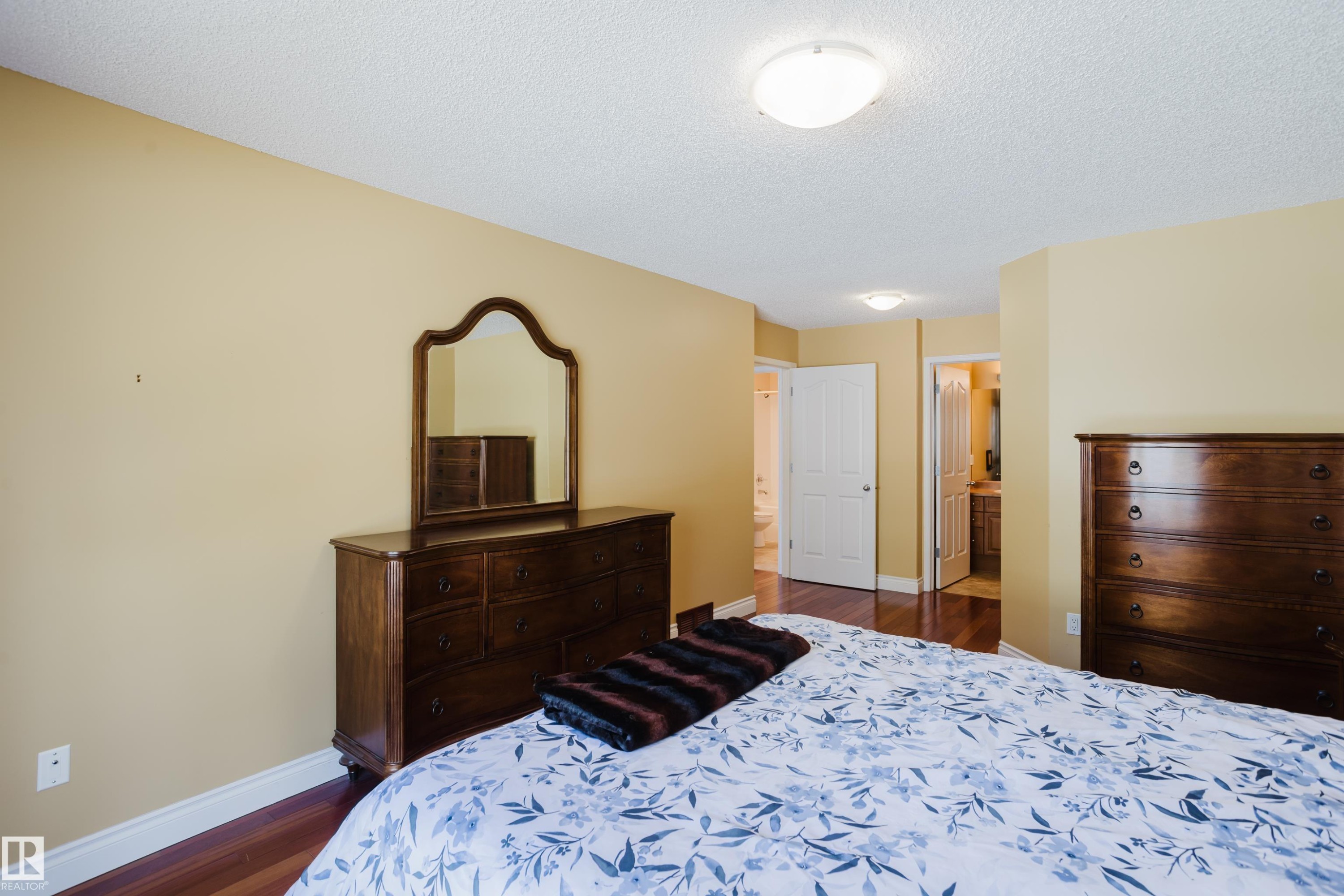 Spacious bedroom featuring wood-finish flooring, light-toned walls, and a ceiling-mounted light fixture - 9 102 Bridgeport Crossing, Leduc, AB - Indoor Photo Showing Bedroom