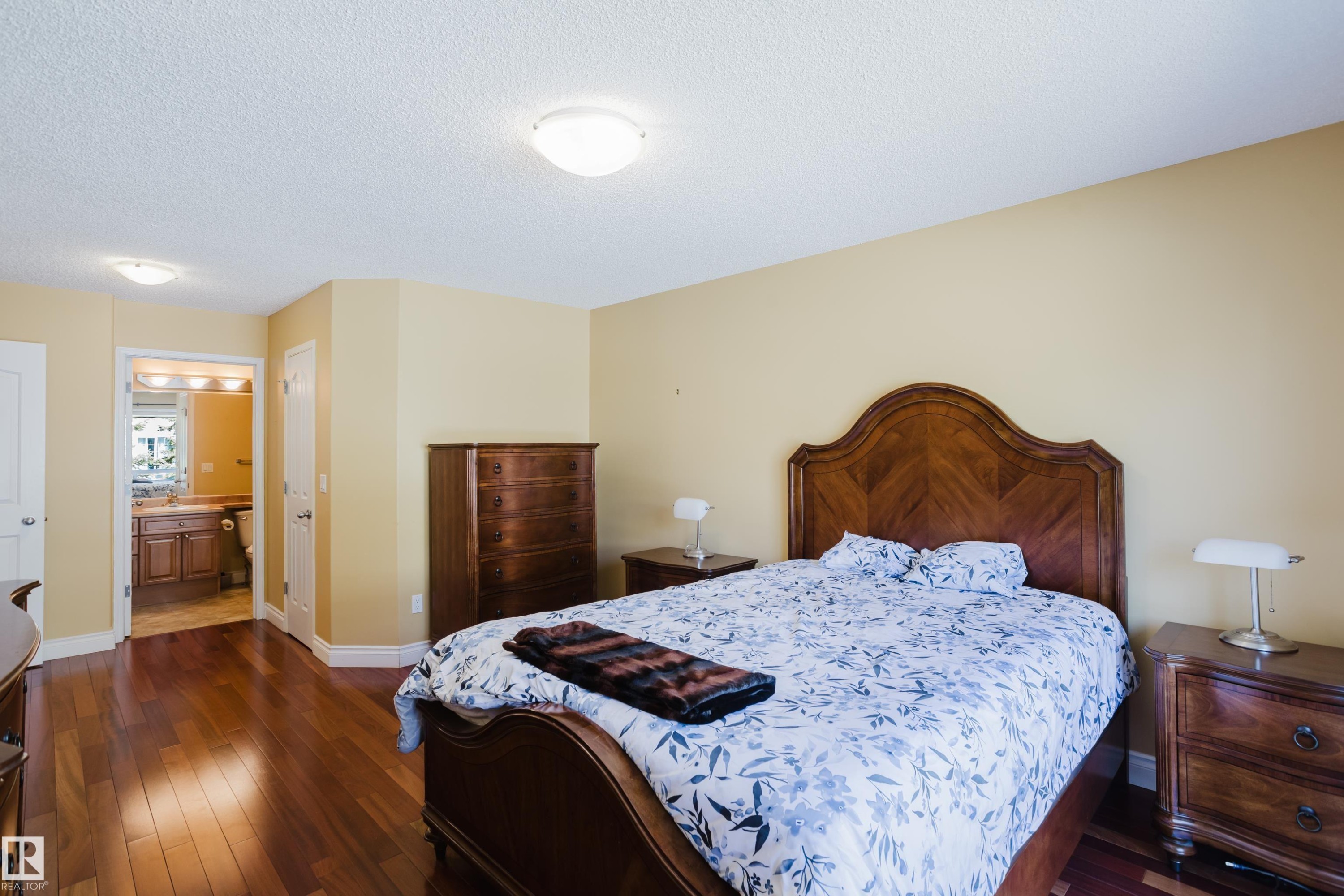 Spacious room featuring wood-finish flooring, light yellow walls, and a textured white ceiling - 9 102 Bridgeport Crossing, Leduc, AB - Indoor Photo Showing Bedroom