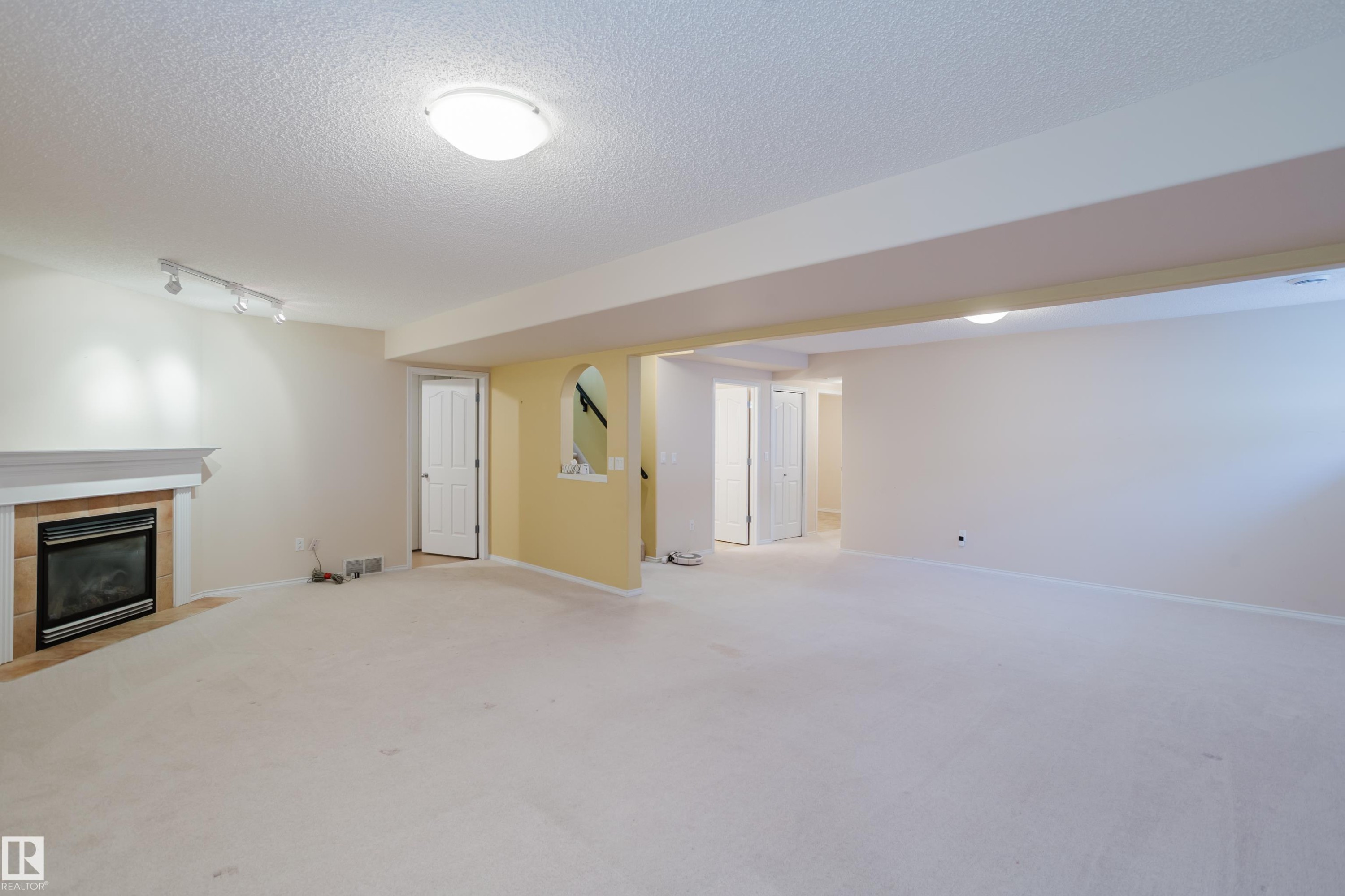 Spacious room featuring carpeting and a recessed fireplace with a white mantel and tile surround - 9 102 Bridgeport Crossing, Leduc, AB - Indoor With Fireplace