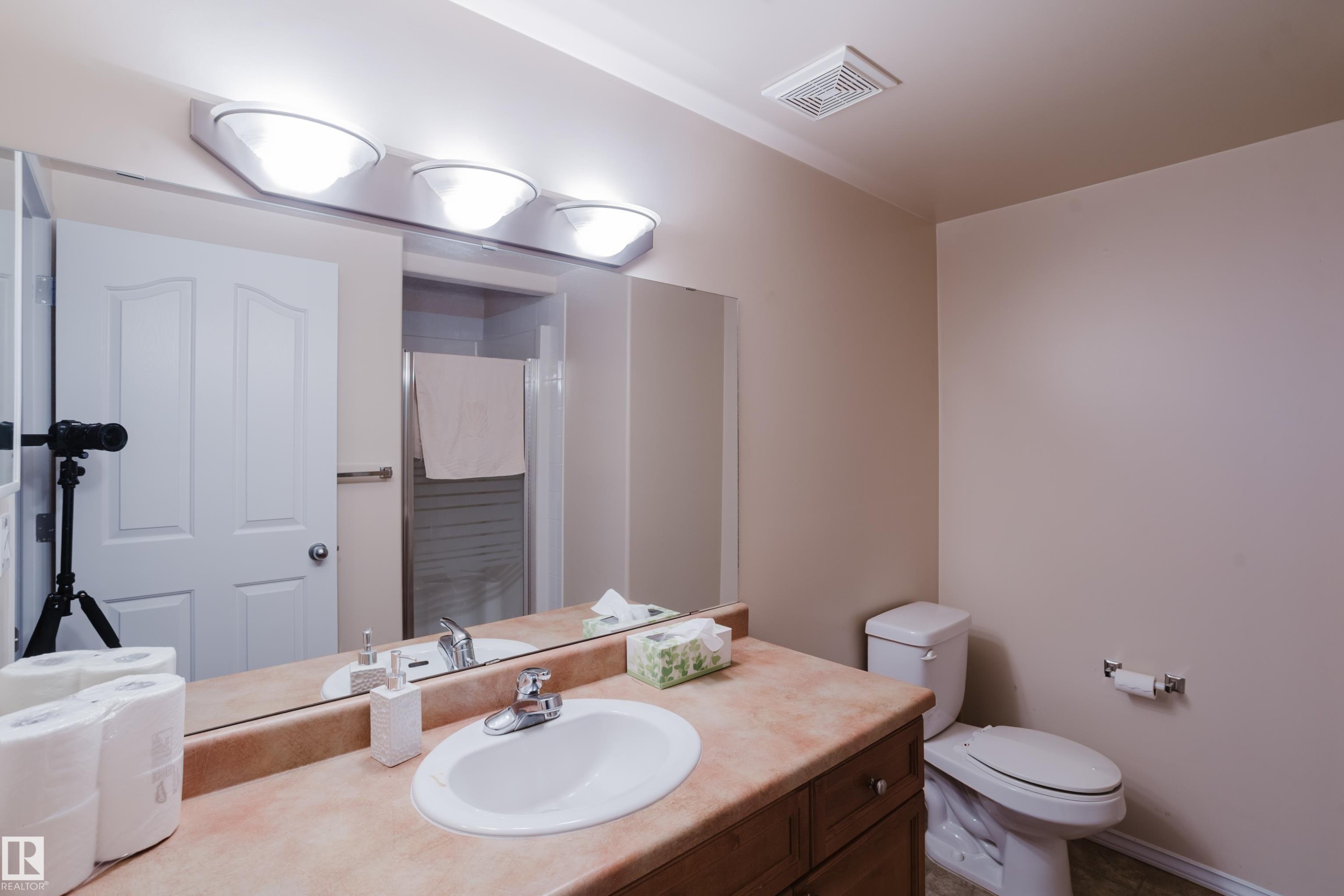 Bathroom featuring a vanity with a drop-in sink, a neutral-toned countertop, and a vanity light fixture - 9 102 Bridgeport Crossing, Leduc, AB - Indoor Photo Showing Bathroom