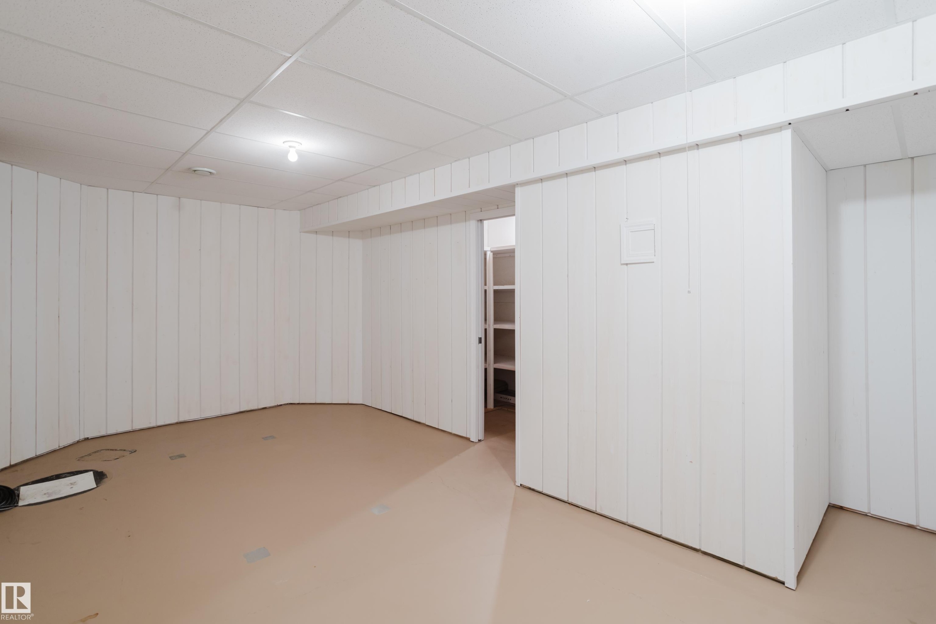Room featuring white vertical paneling and a suspended ceiling system perfect for a potential workshop - 9 102 Bridgeport Crossing, Leduc, AB - Indoor Photo Showing Other Room