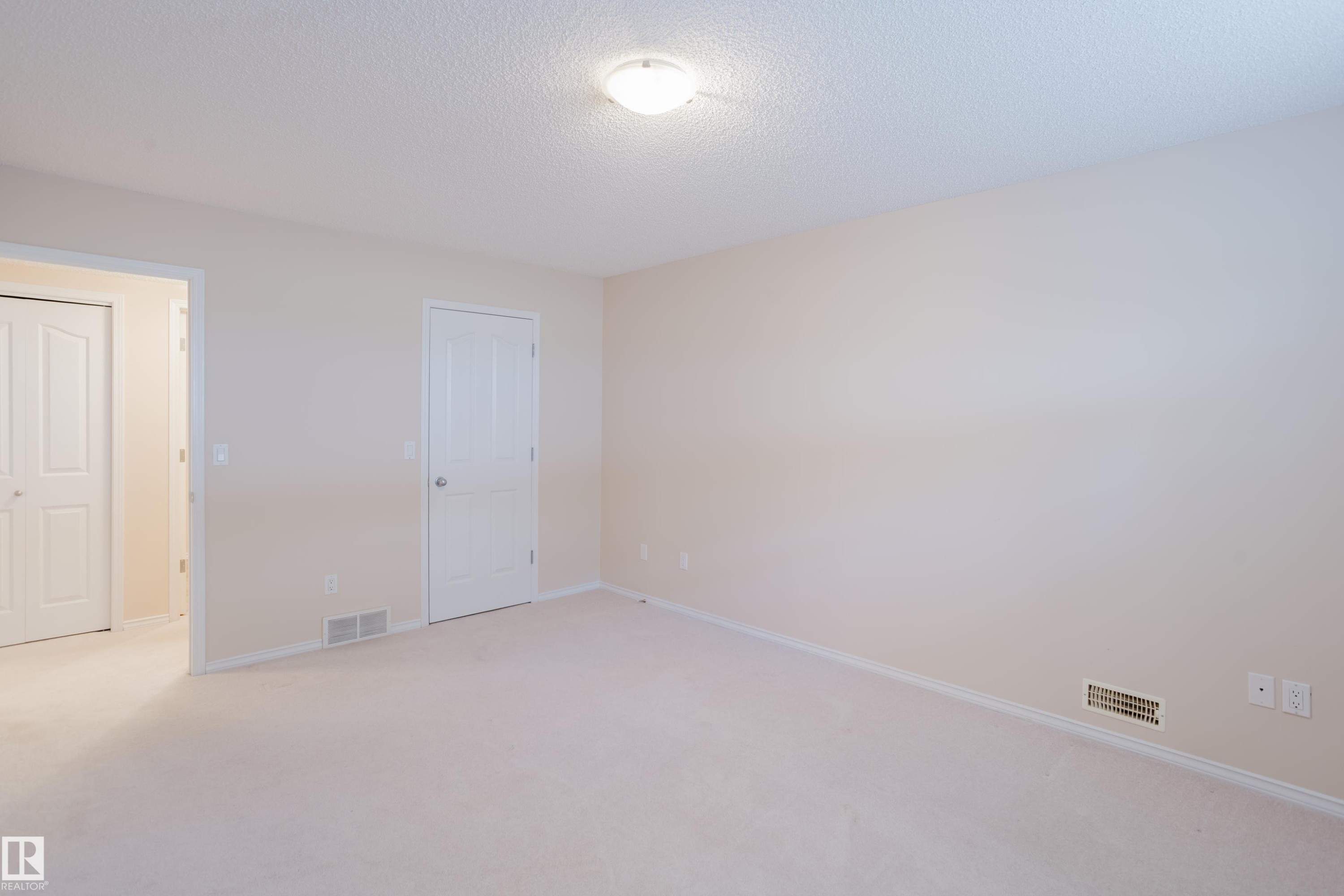 Spacious room with light-toned carpet flooring, light-colored walls, and white trim - 9 102 Bridgeport Crossing, Leduc, AB - Indoor Photo Showing Other Room