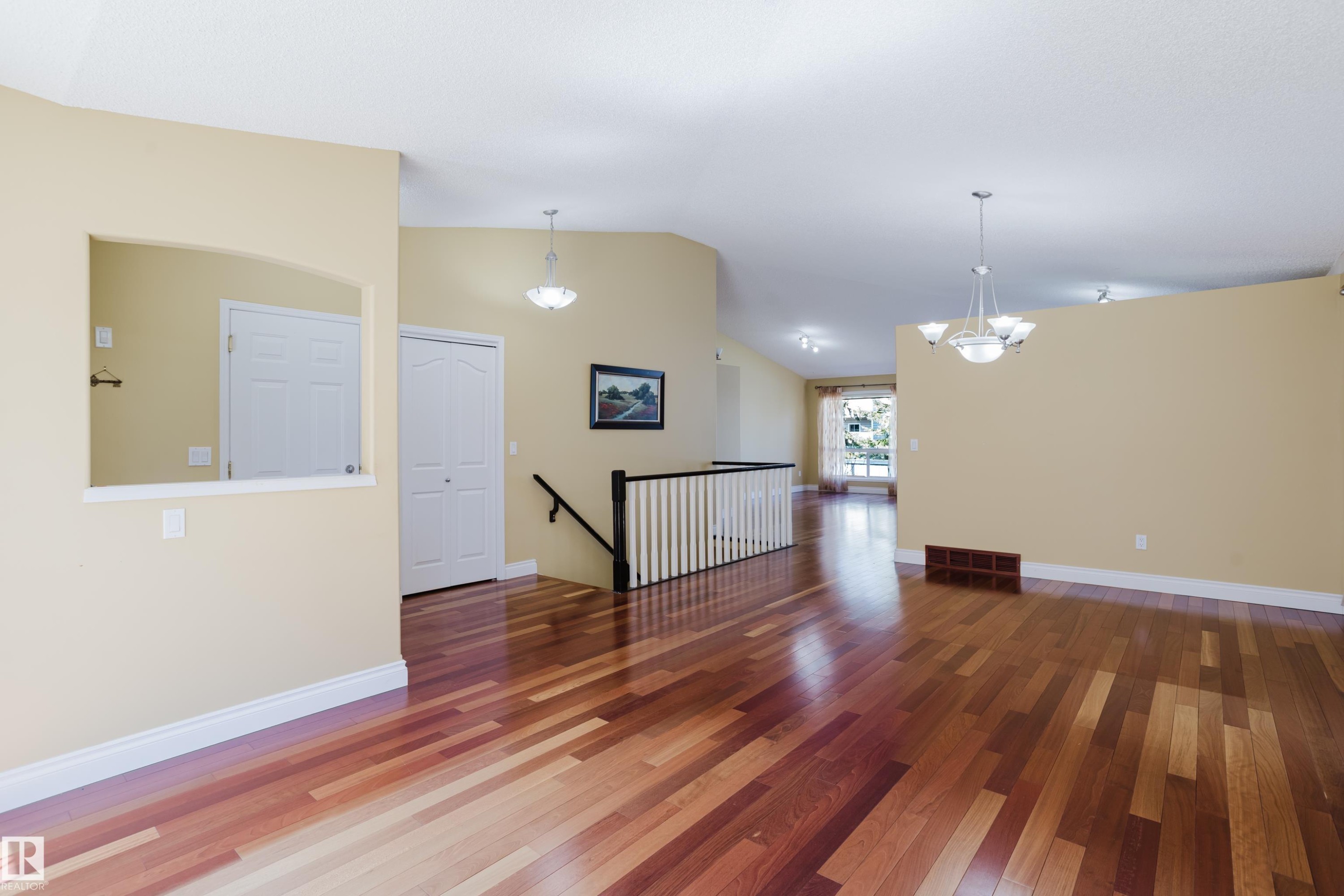 Expansive interior space featuring wood-finish flooring, light-colored walls, and a vaulted ceiling - 9 102 Bridgeport Crossing, Leduc, AB - Indoor Photo Showing Other Room