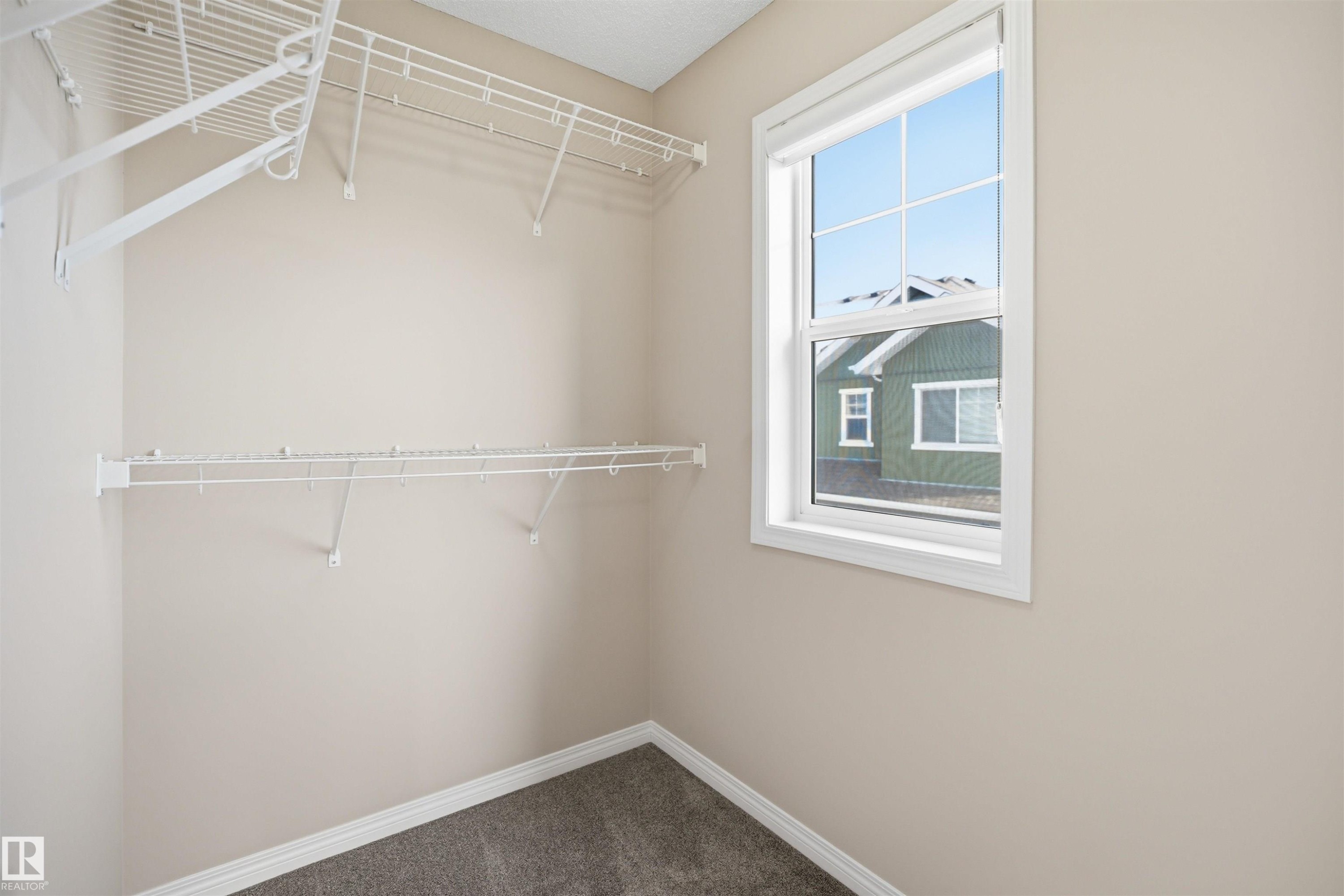 Walk-in closet featuring wire shelving, neutral wall paint, and gray carpet flooring - 33 7385 Edgemont Way Nw, Edmonton, AB - Indoor With Storage