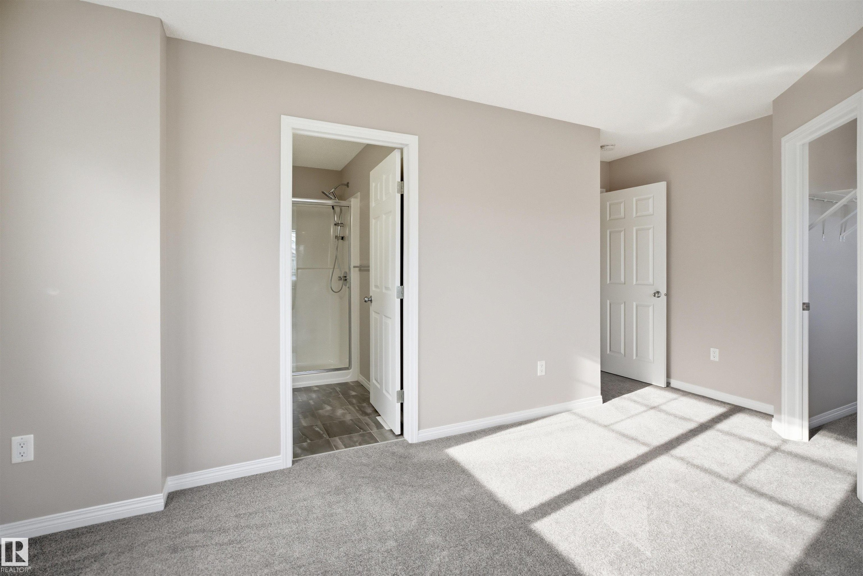 Spacious room featuring light neutral wall paint, white trim, and gray carpet flooring - 33 7385 Edgemont Way Nw, Edmonton, AB - Indoor Photo Showing Other Room