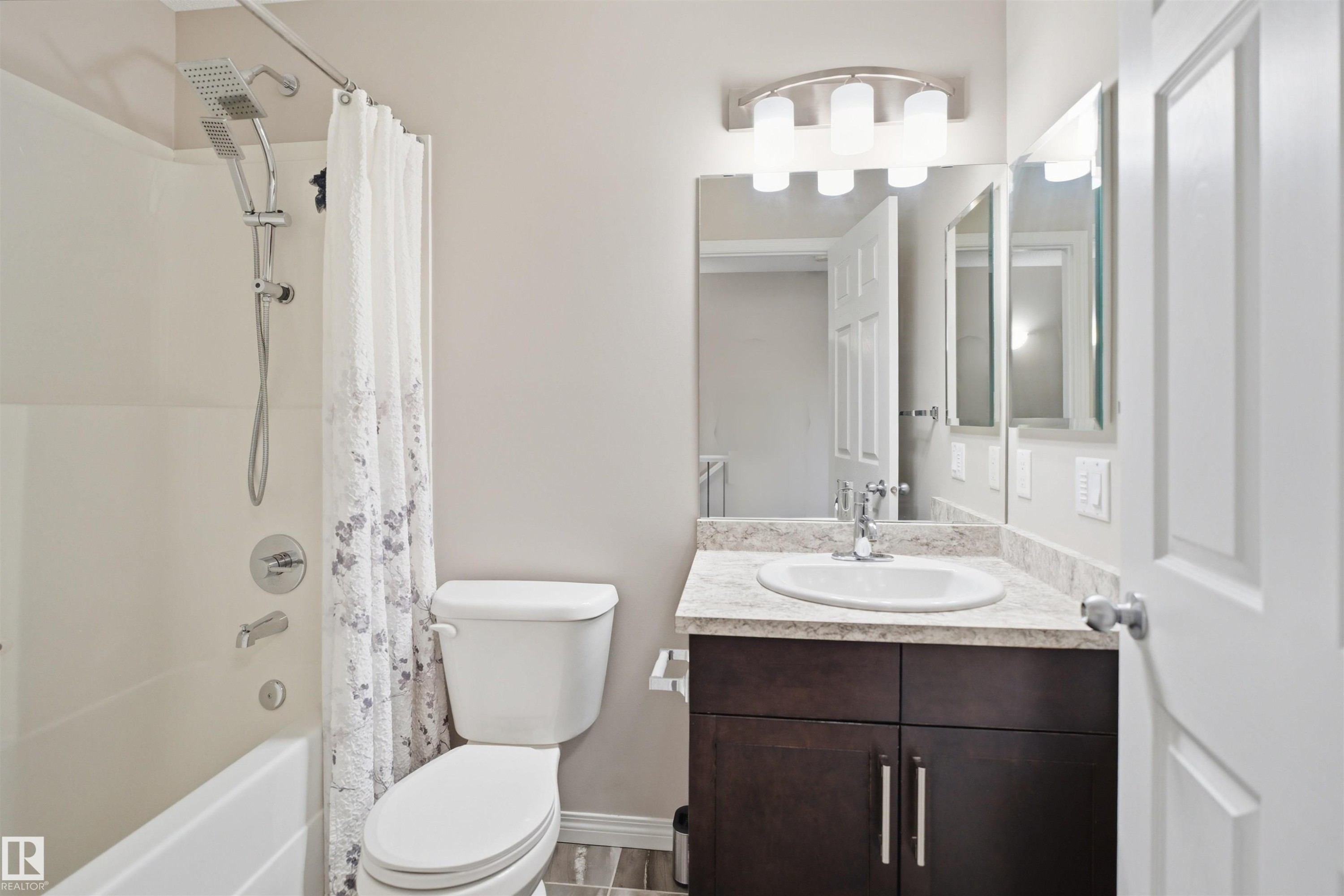 Bathroom featuring a vanity with a dark wood-finish cabinet, light-toned countertop, and an oval undermount sink - 33 7385 Edgemont Way Nw, Edmonton, AB - Indoor Photo Showing Bathroom