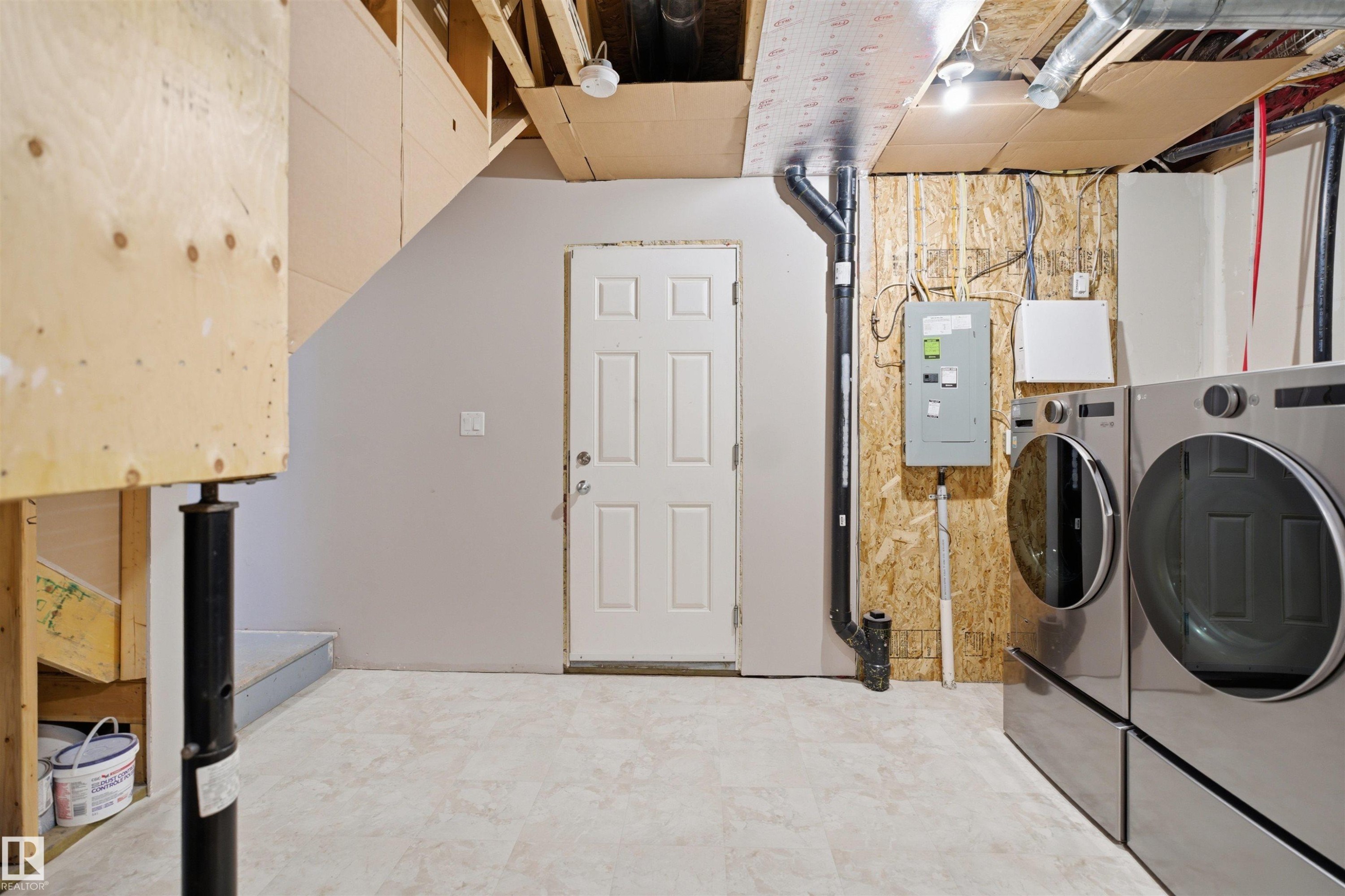Unfinished basement area featuring a utility door, electrical panel, exposed framing, and vinyl flooring - 33 7385 Edgemont Way Nw, Edmonton, AB - Indoor Photo Showing Laundry Room