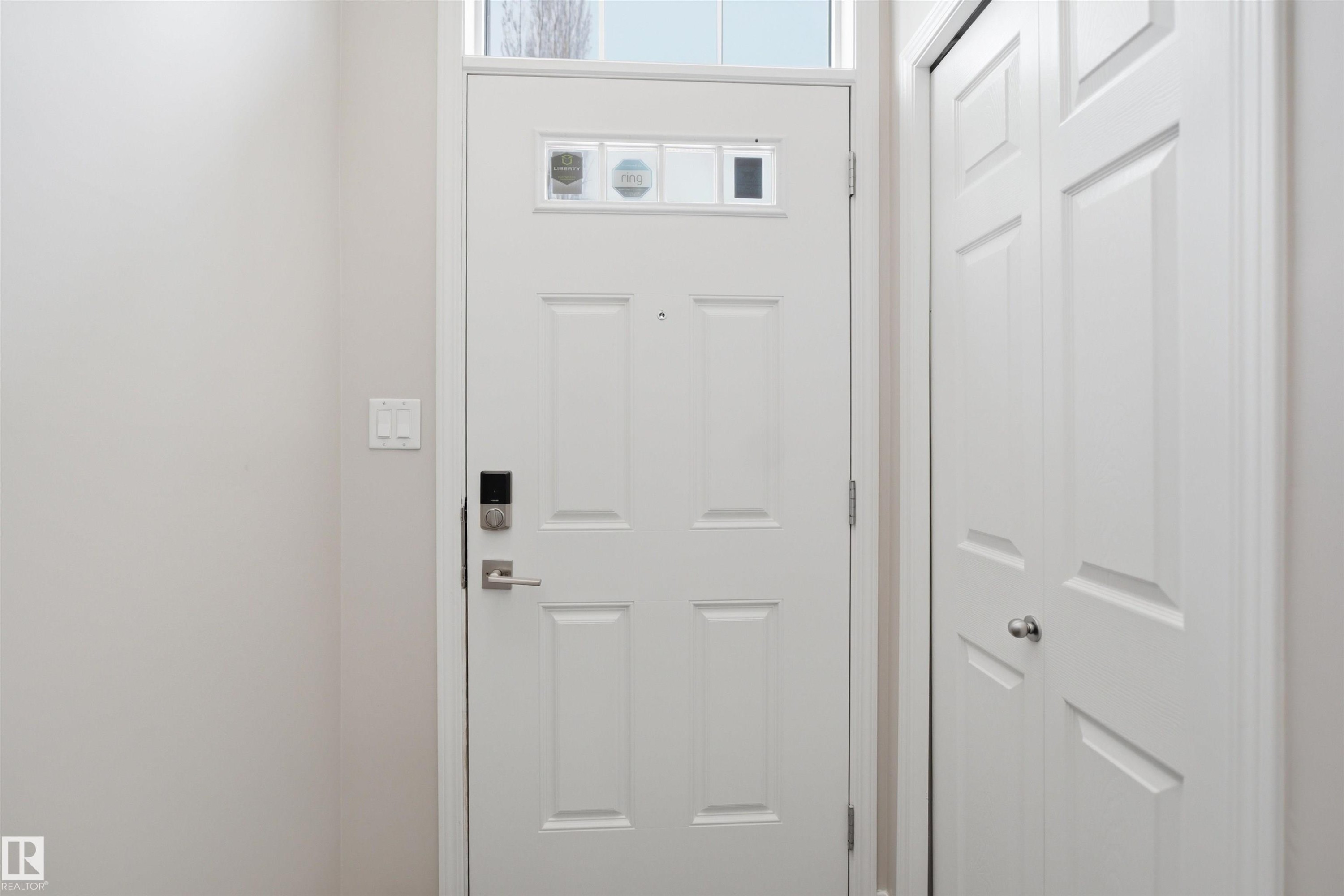 White paneled entry door with transom window, electronic keypad lock, and brushed nickel hardware - 33 7385 Edgemont Way Nw, Edmonton, AB - Indoor Photo Showing Other Room