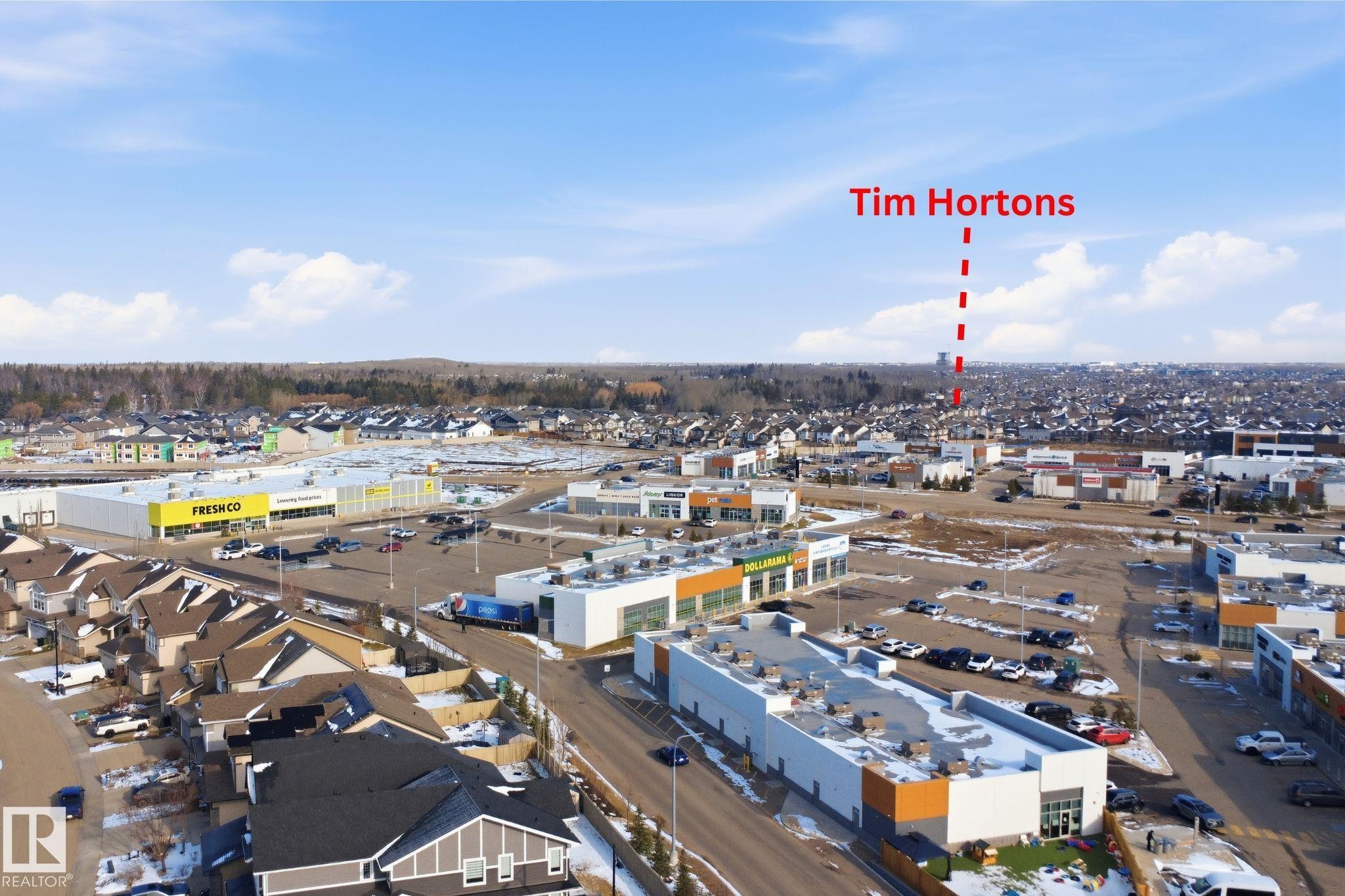 Aerial perspective showcasing a retail complex with multiple commercial buildings, ample surface parking, and surrounding residential properties - 33 7385 Edgemont Way Nw, Edmonton, AB - Outdoor With View