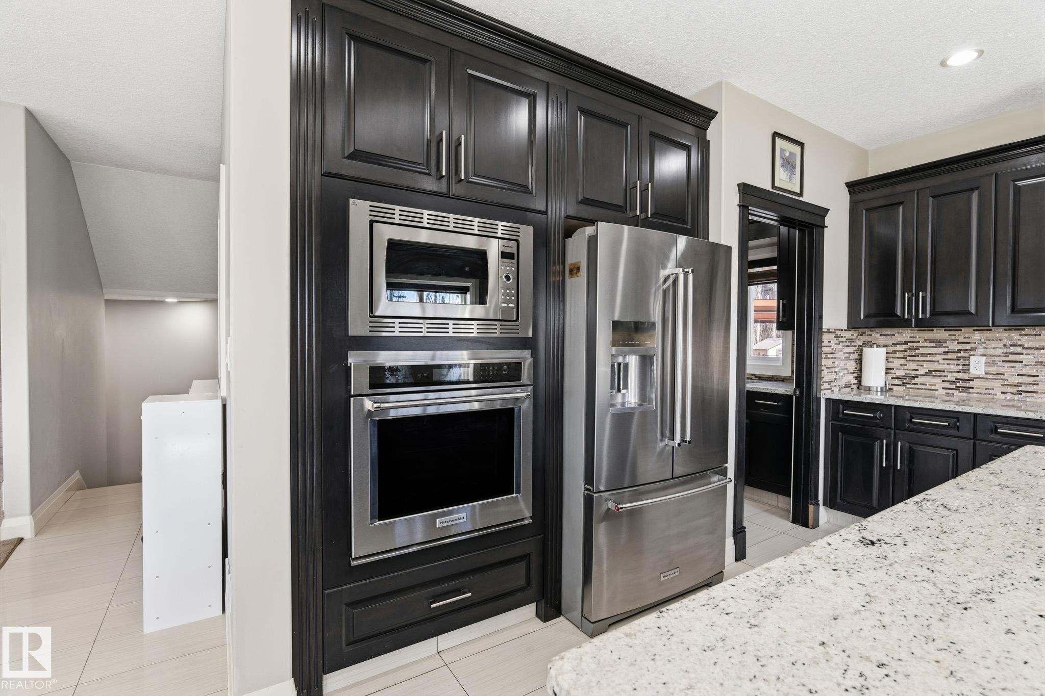 Integrated stainless steel appliances within dark wood-finish cabinetry - 731 57 Street Sw, Edmonton, AB - Indoor Photo Showing Kitchen With Upgraded Kitchen