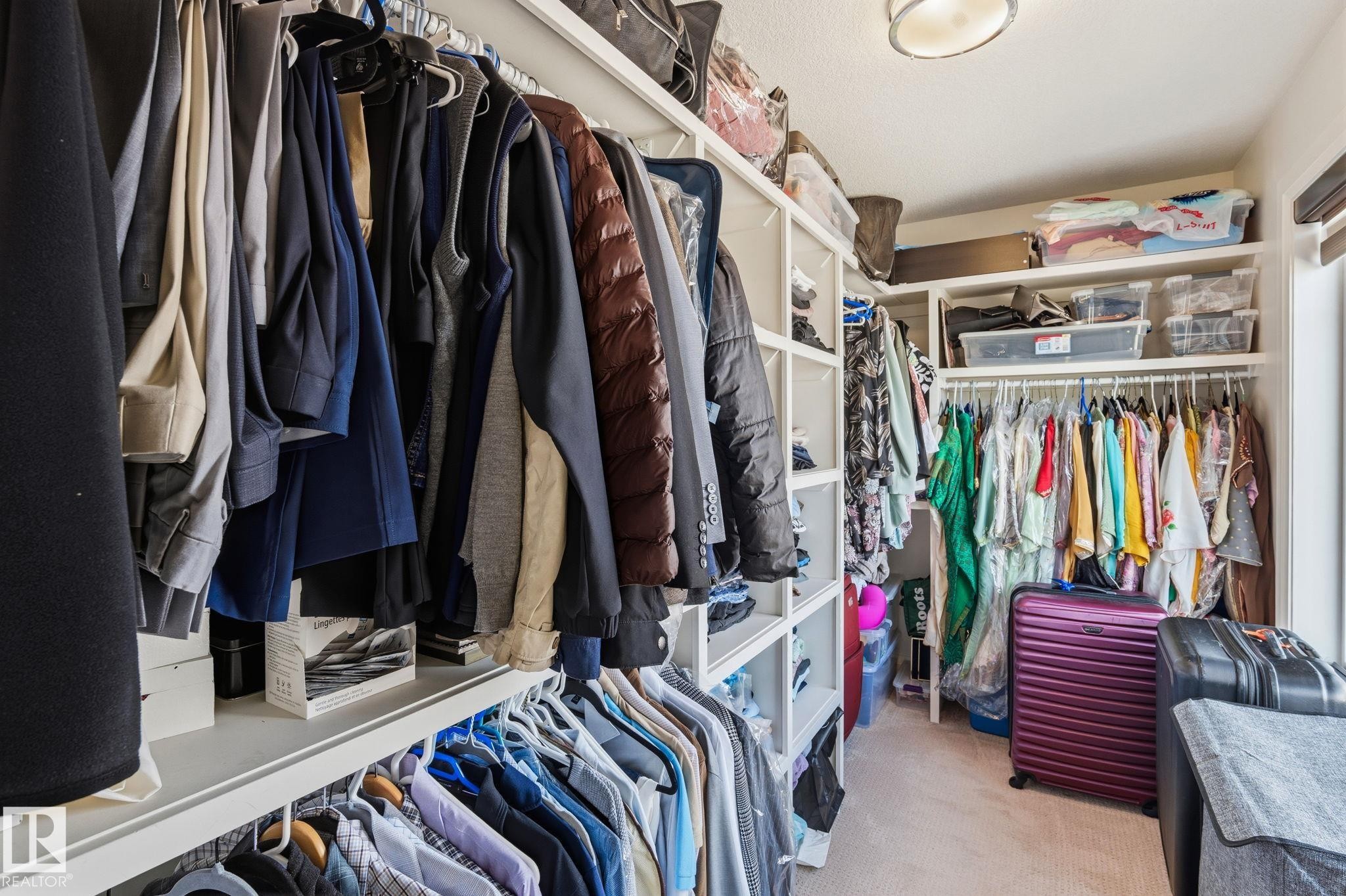 Custom closet system featuring multiple hanging rods, integrated shelving, and a neutral carpeted floor - 731 57 Street Sw, Edmonton, AB - Indoor With Storage