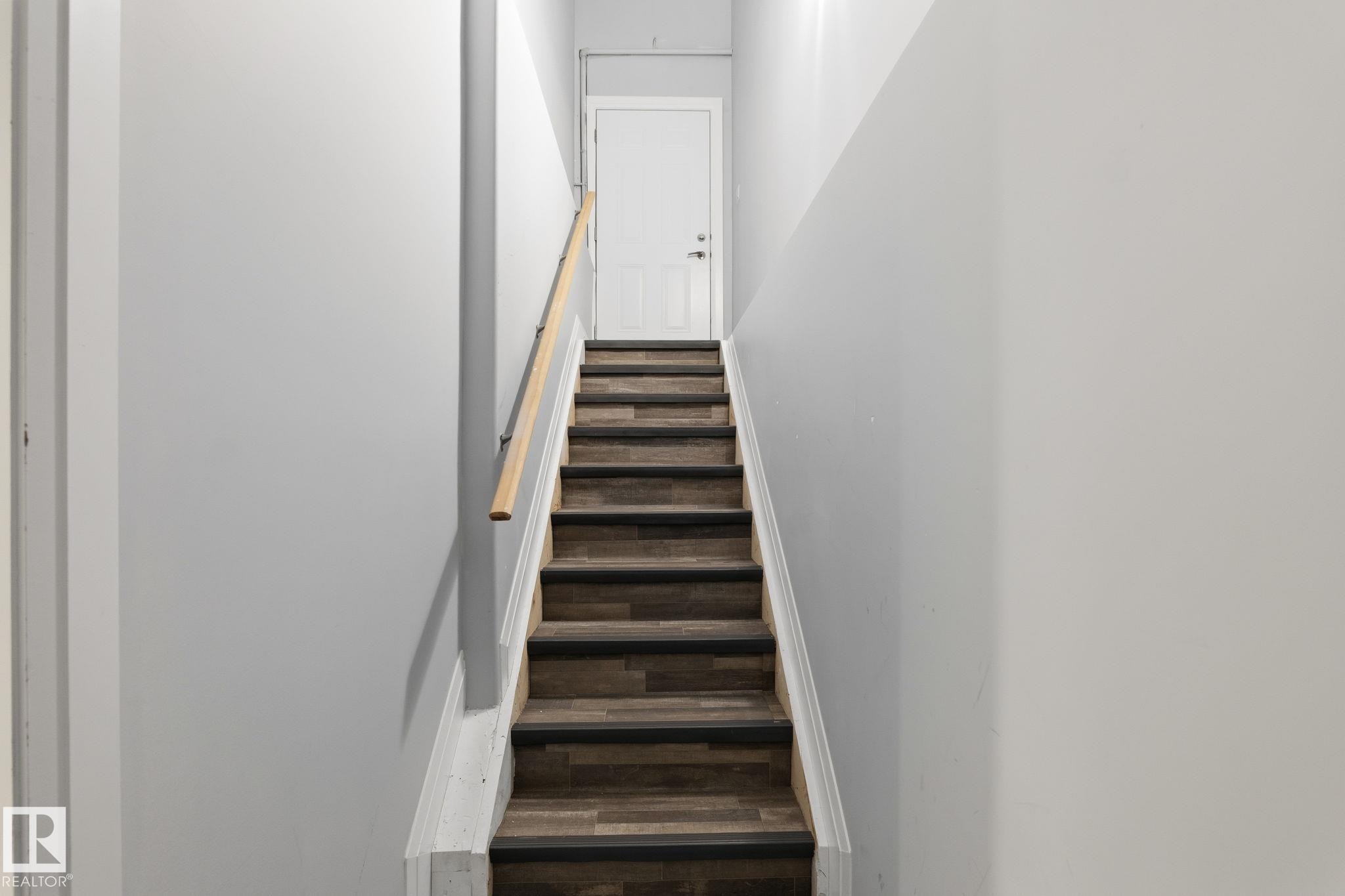 Staircase featuring wood-finish treads with dark risers, a light wood-tone handrail, and white side stringers - 731 57 Street Sw, Edmonton, AB - Indoor Photo Showing Other Room