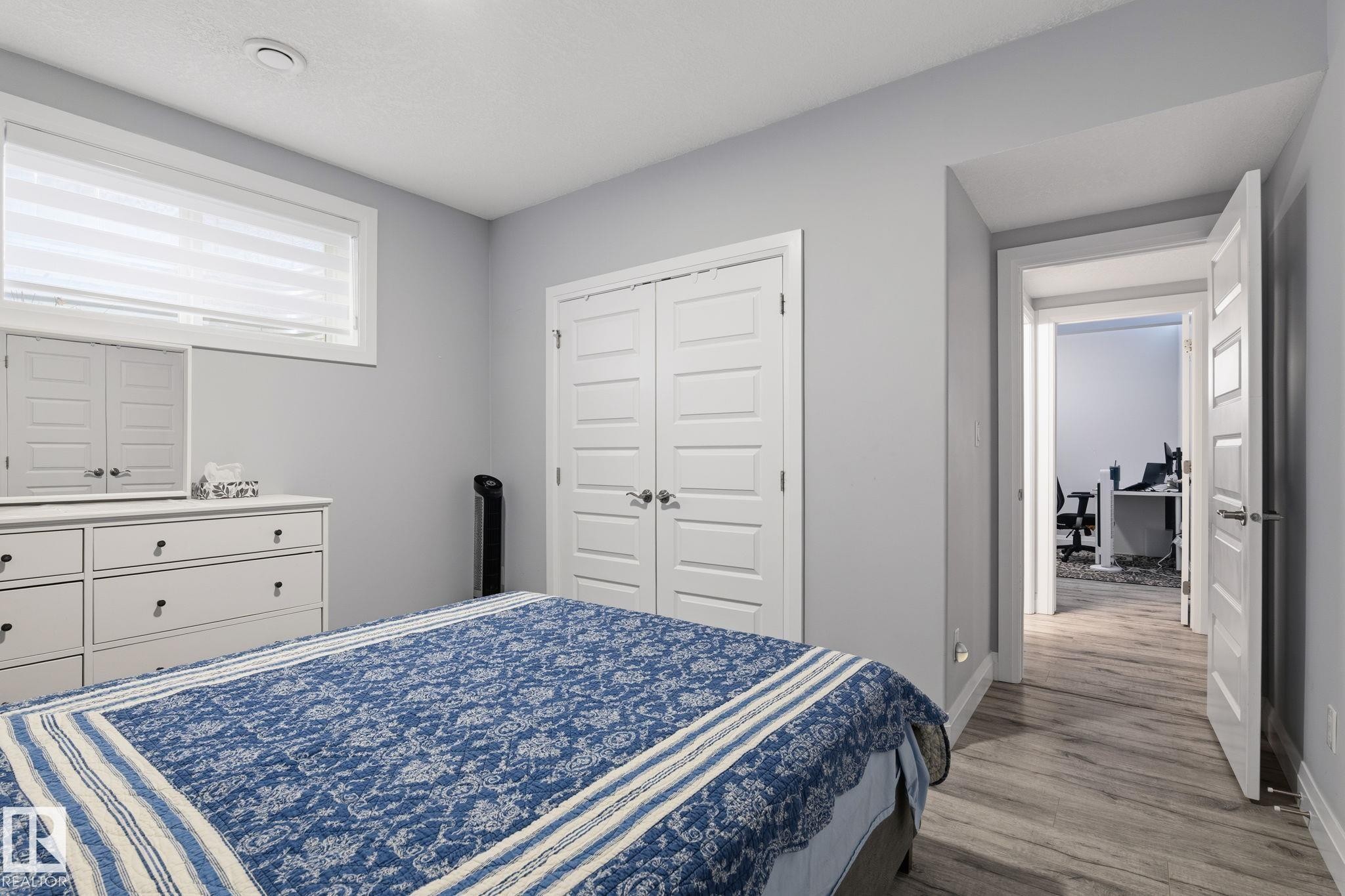Interior space featuring light gray walls, wood-finish flooring, white trim, and a window with blinds - 731 57 Street Sw, Edmonton, AB - Indoor Photo Showing Bedroom