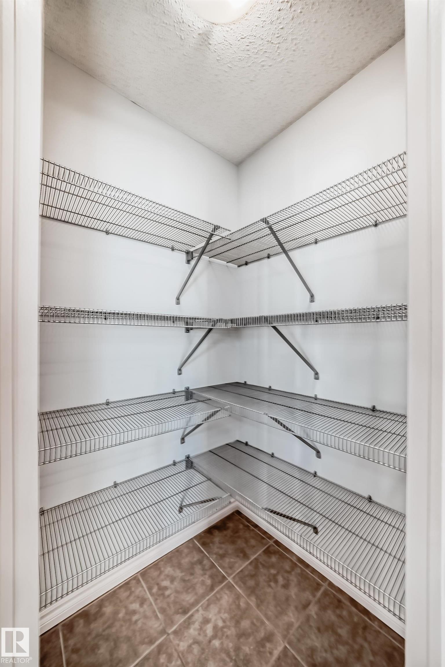 Corner pantry featuring multiple levels of wire shelving and diagonal tile flooring - 6723 19 Avenue, Edmonton, AB - Indoor With Storage