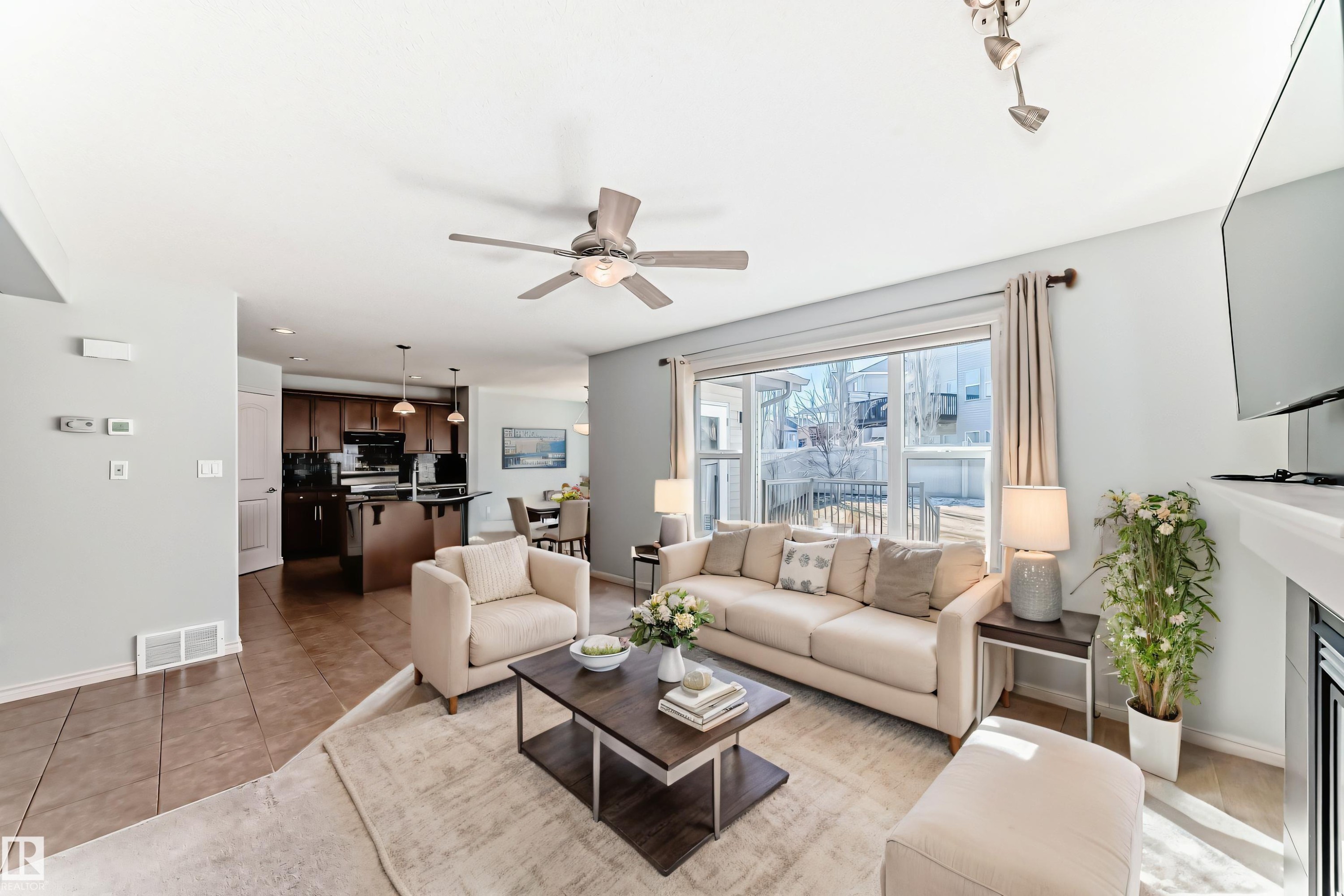 Open-concept living area featuring light-toned walls, a ceiling fan, and large sliding glass doors - 6723 19 Avenue, Edmonton, AB - Indoor Photo Showing Living Room With Fireplace