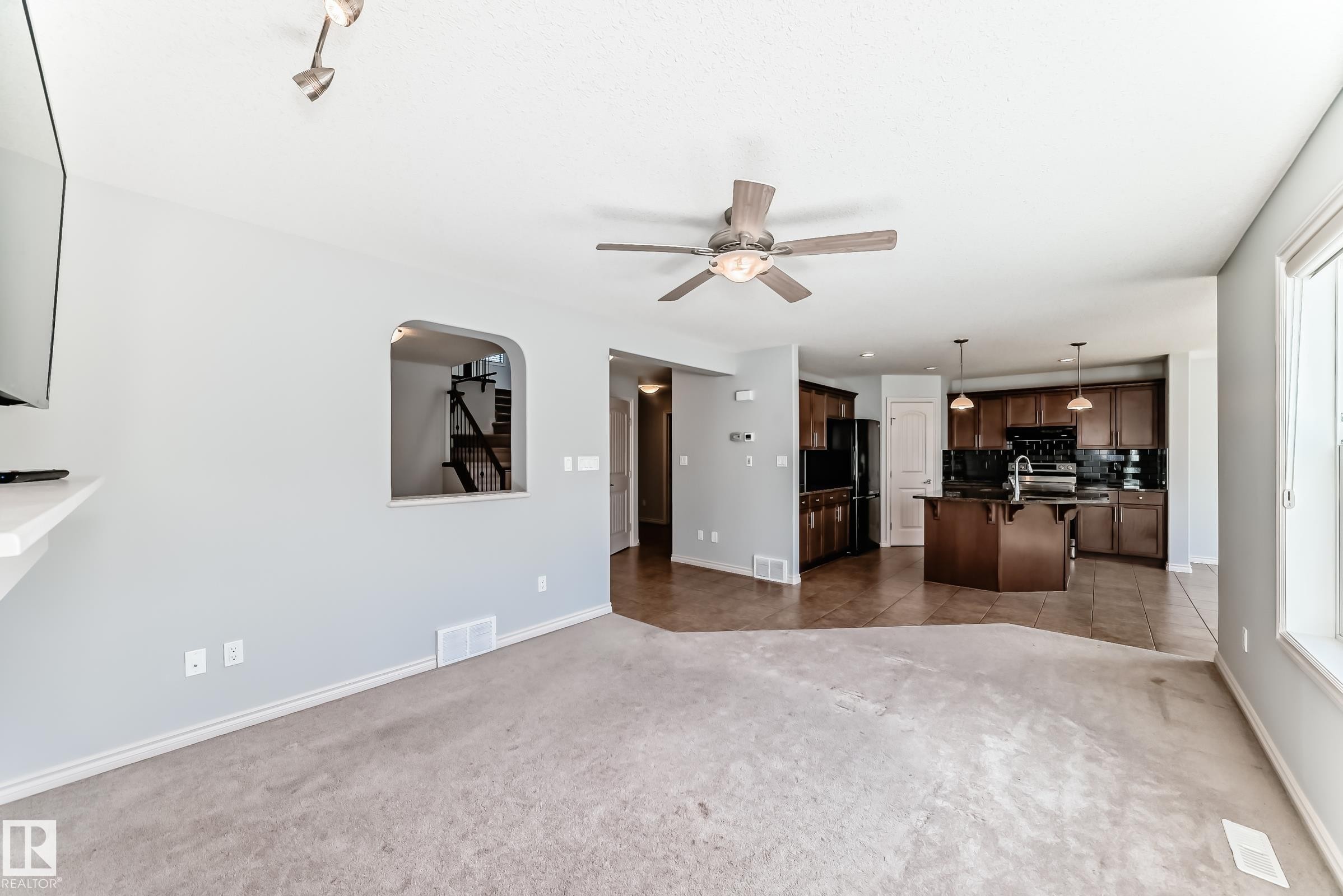 Open-concept living space featuring light gray walls, carpet flooring, and a ceiling fan with integrated lighting - 6723 19 Avenue, Edmonton, AB - Indoor