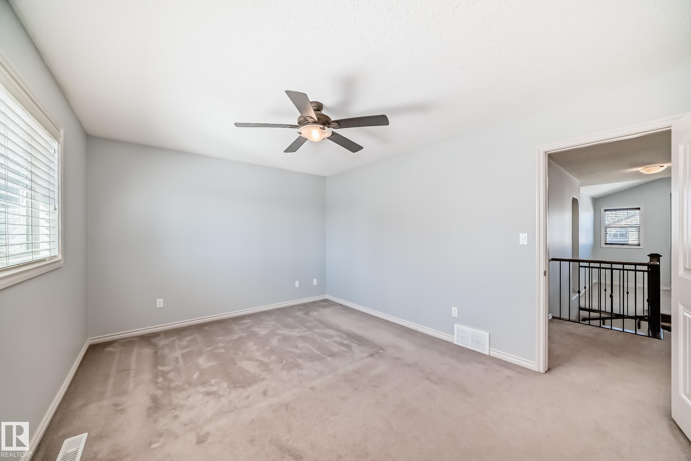Spacious room featuring vaulted ceilings, a ceiling fan with integrated lighting, window with blinds, light gray wall paint, and neutral carpeting - 6723 19 Avenue, Edmonton, AB - Indoor Photo Showing Other Room