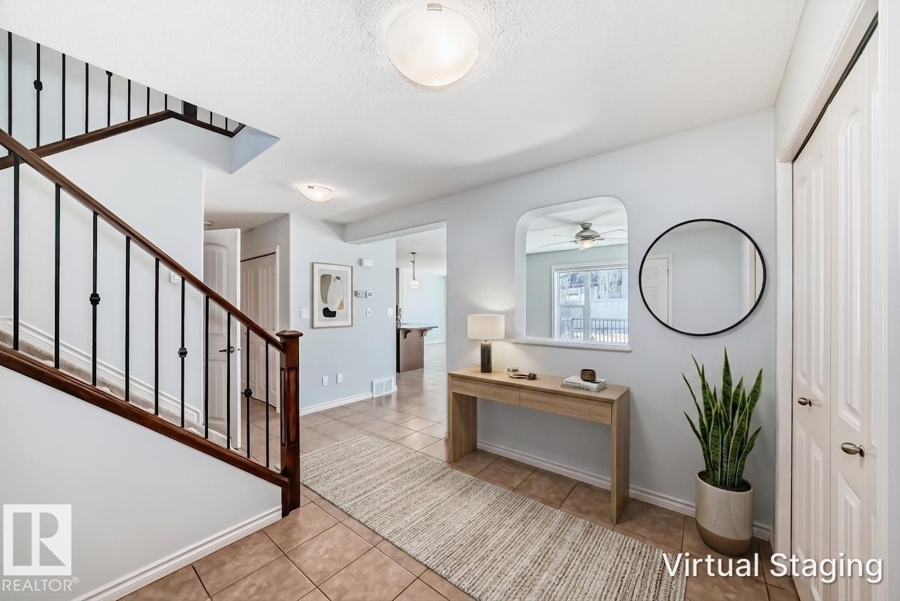 Foyer featuring ceramic tile flooring, a wood and iron staircase, and light blue wall tones - 6723 19 Avenue, Edmonton, AB - Indoor Photo Showing Other Room