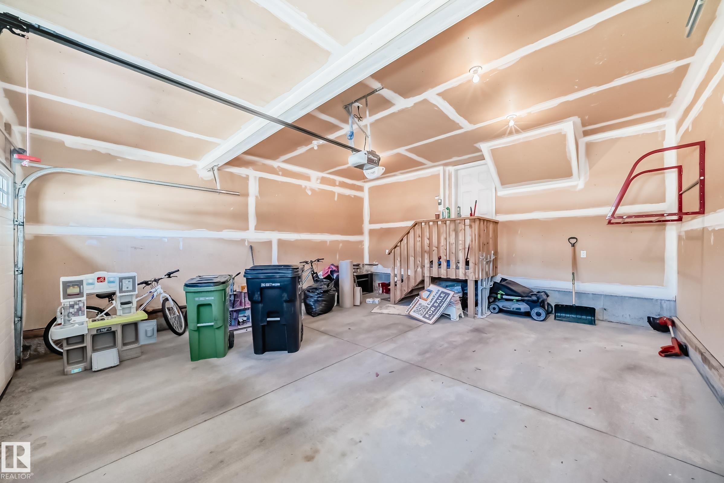 Spacious garage featuring a concrete floor, exposed ceiling joists, and an interior staircase providing access - 6723 19 Avenue, Edmonton, AB - Indoor Photo Showing Garage