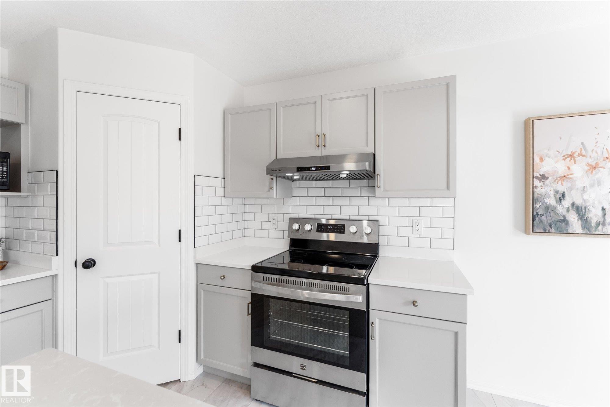Kitchen area featuring light gray cabinetry, stainless steel range and hood, white subway tile backsplash, and light-toned countertops - 326 Silver Berry Road, Edmonton, AB - Indoor Photo Showing Kitchen