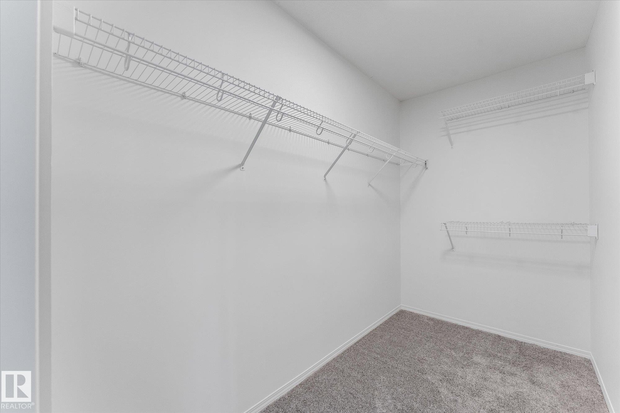 Closet featuring wire shelving, wire hanging rods, neutral wall paint, white baseboards, and gray textured carpeting - 326 Silver Berry Road, Edmonton, AB - Indoor With Storage