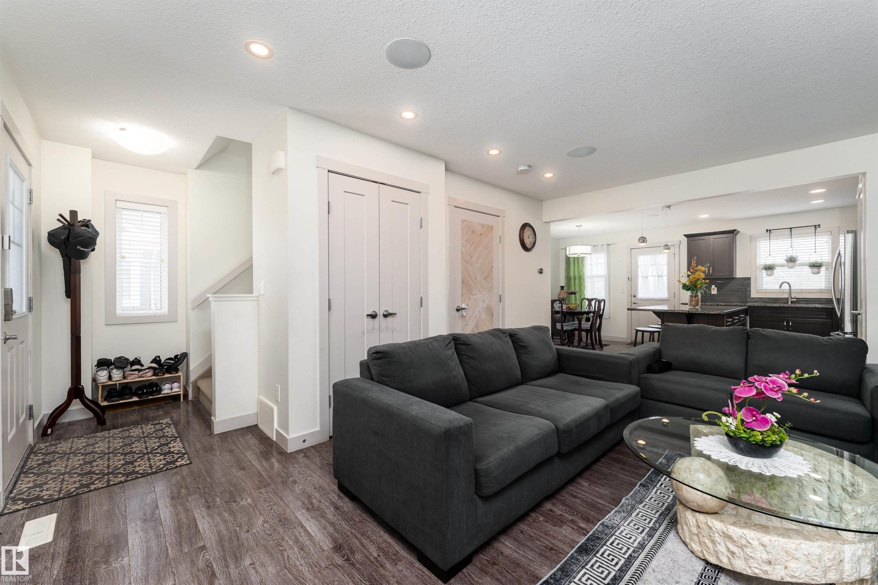 Open-concept living space featuring wood-finish flooring, recessed lighting, white trim, and a kitchen with dark cabinetry and a central island - 15 5203 149 Avenue, Edmonton, AB - Indoor Photo Showing Living Room