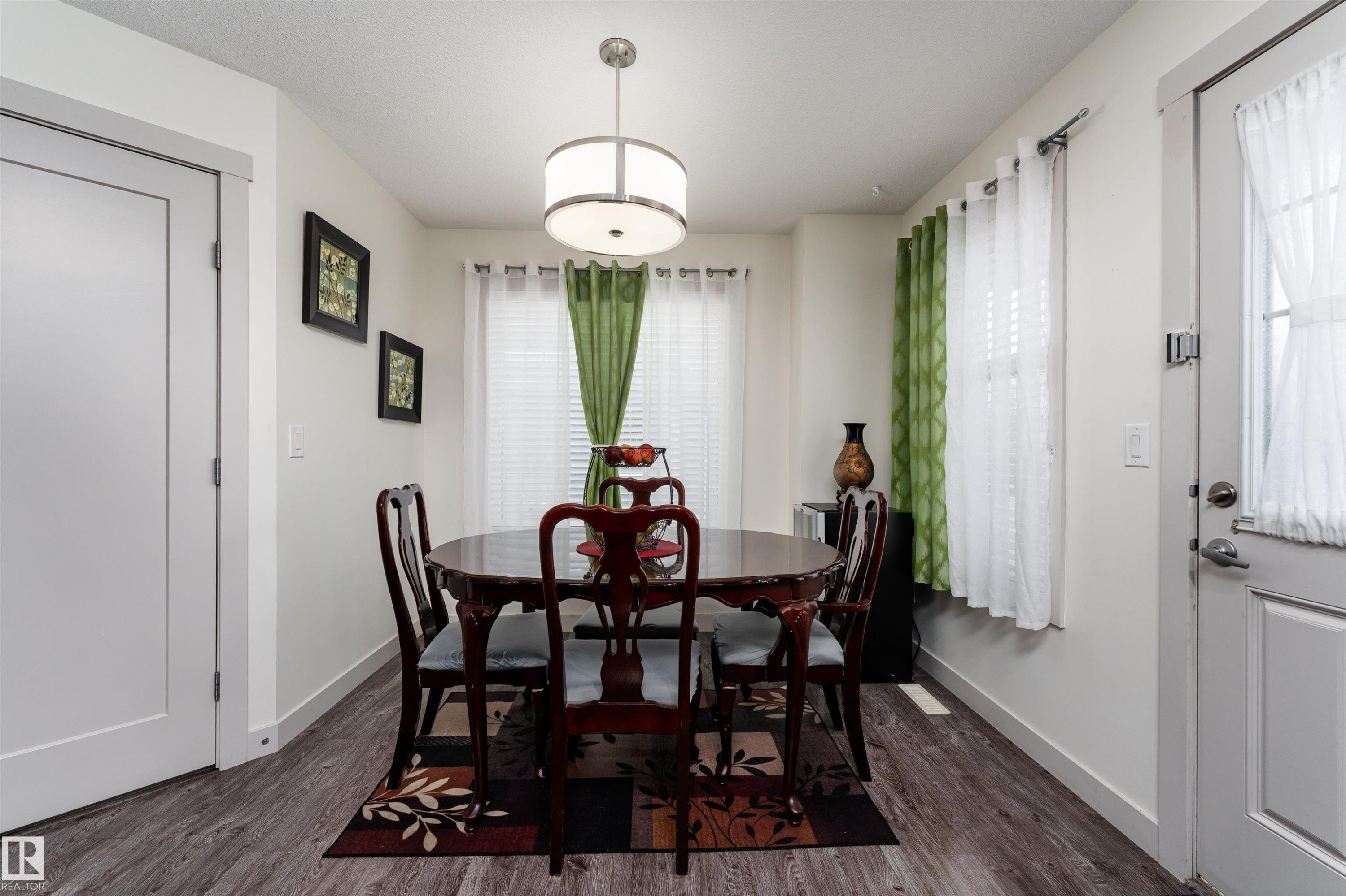 Dining space featuring wood-finish flooring and a contemporary drum pendant light fixture - 15 5203 149 Avenue, Edmonton, AB - Indoor Photo Showing Dining Room
