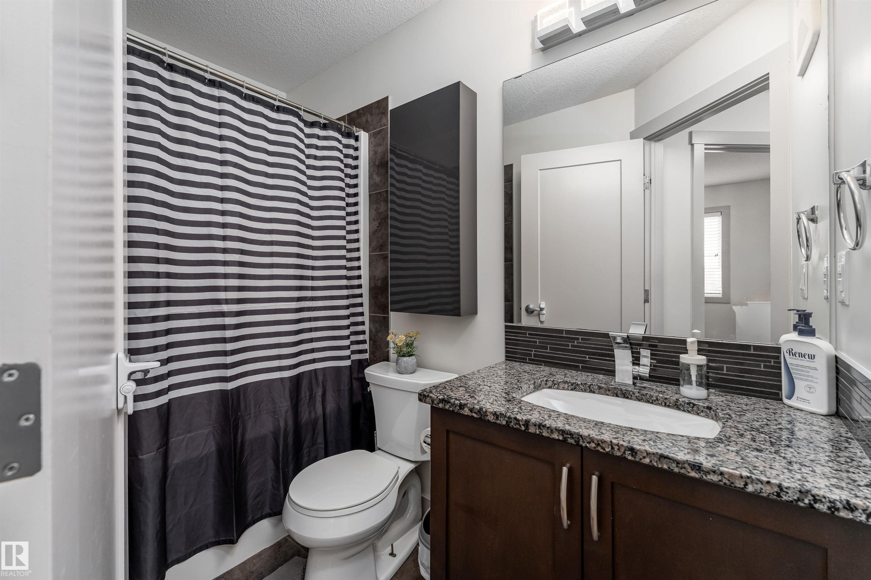Bathroom featuring a vanity with granite countertop, integrated sink, and dark wood cabinetry - 15 5203 149 Avenue, Edmonton, AB - Indoor Photo Showing Bathroom