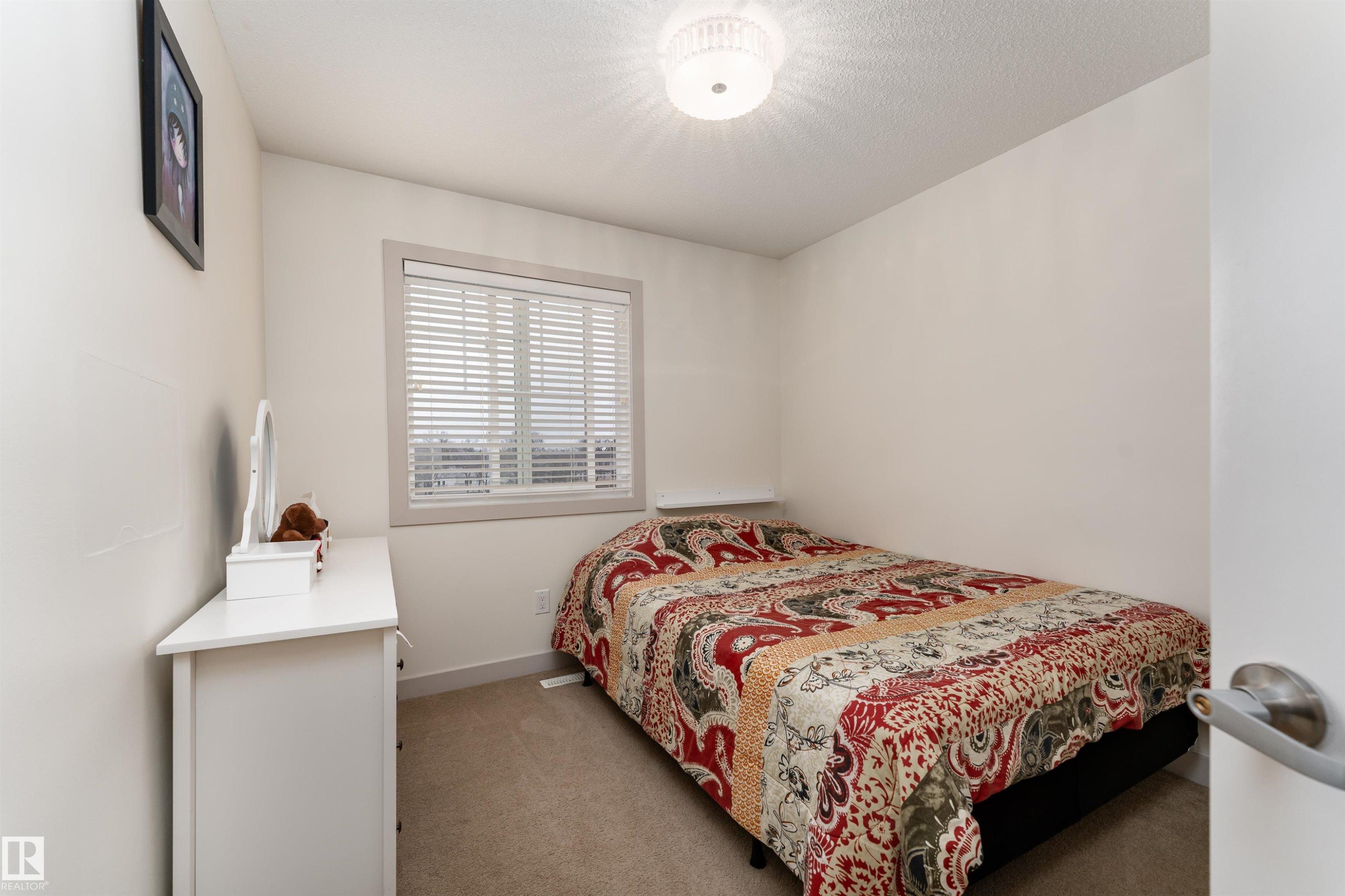 Bedroom featuring neutral-toned walls, carpeted flooring, and a single window with blinds - 15 5203 149 Avenue, Edmonton, AB - Indoor Photo Showing Bedroom