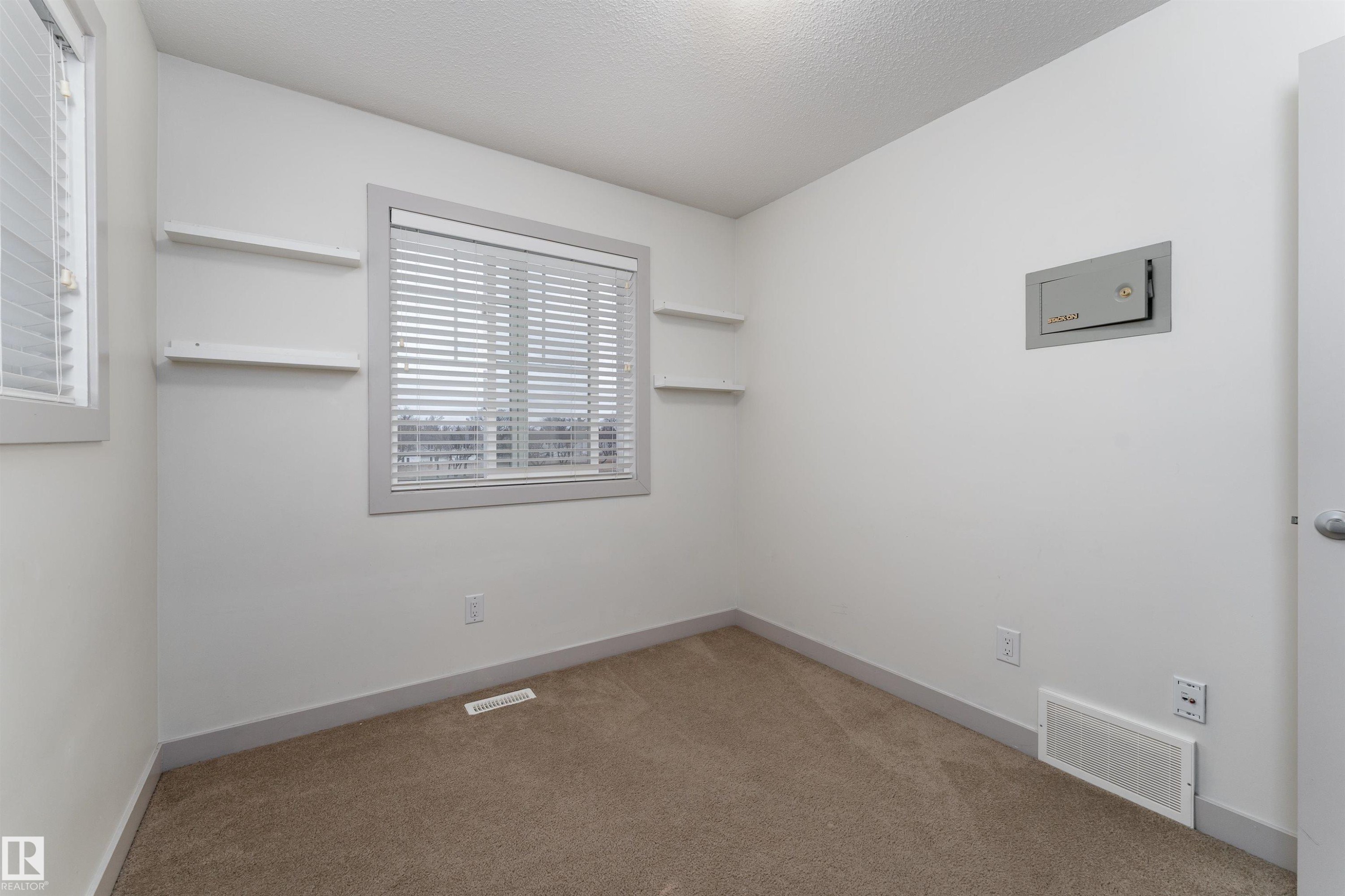 Carpeted room with a large window featuring horizontal blinds - 15 5203 149 Avenue, Edmonton, AB - Indoor Photo Showing Other Room