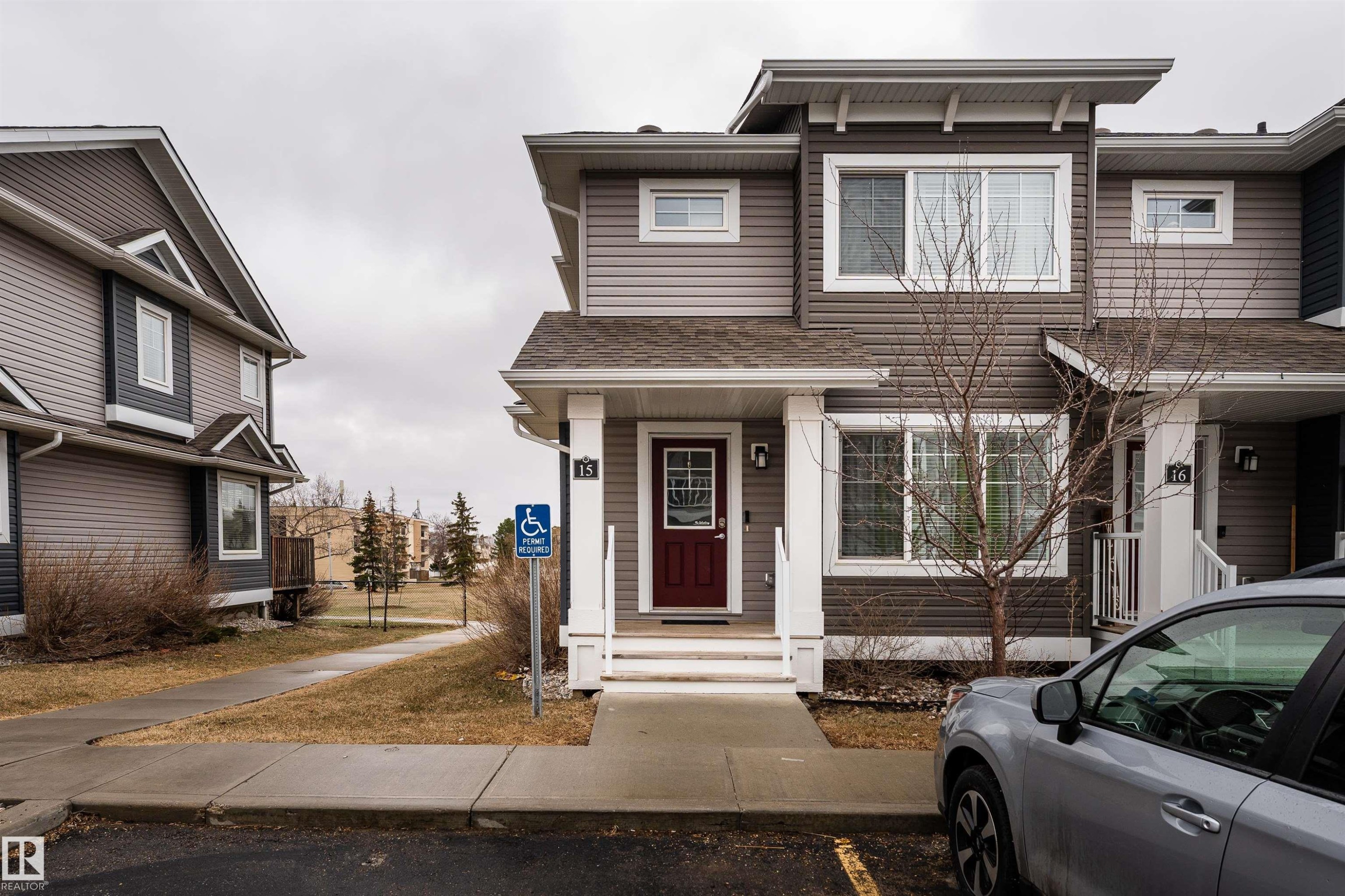 Contemporary townhome exterior featuring multi-toned siding, white trim, a covered entry with a deep red door, and a concrete walkway - 15 5203 149 Avenue, Edmonton, AB - Outdoor