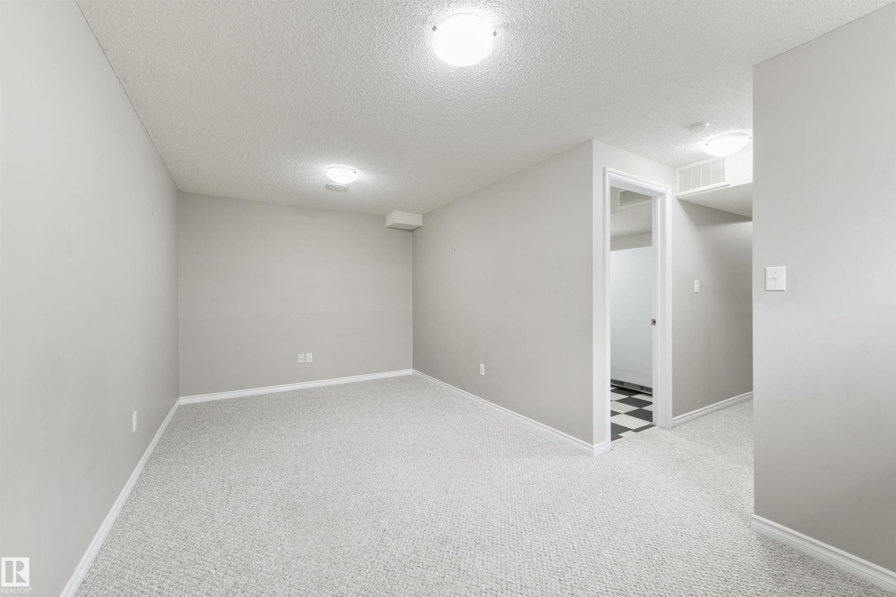 Spacious room featuring light gray carpeting, neutral wall paint, and white baseboards - 2923 30 Street, Edmonton, AB - Indoor