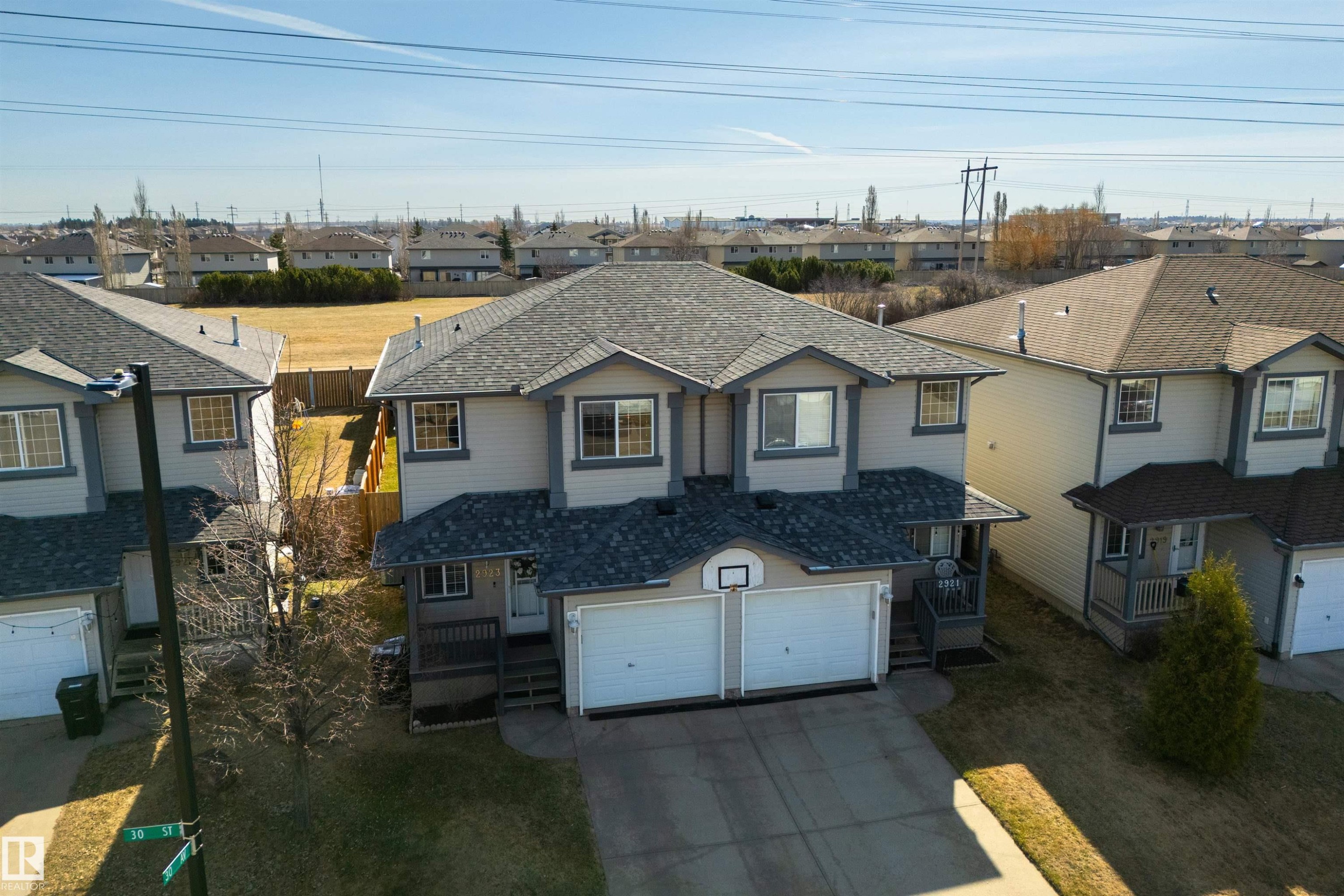 Duplex property featuring a two-car garage, covered entryways, and light-toned siding with dark trim accents - 2923 30 Street, Edmonton, AB - Outdoor