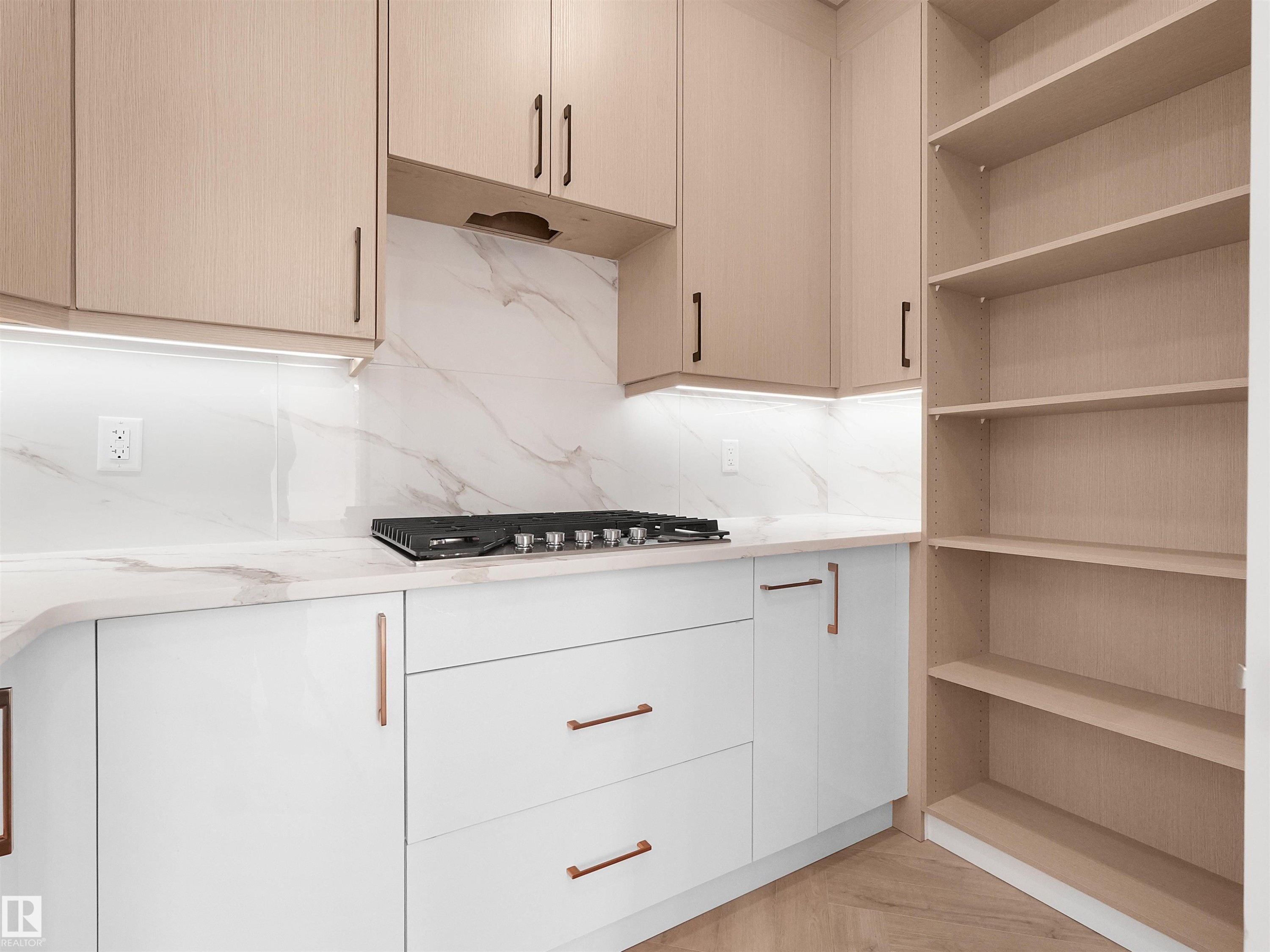 Butlers Kitchen featuring a built-in gas cooktop, under-cabinet lighting, full-height backsplash, light wood-finish upper cabinetry, and white lower cabinetry with coordinating hardware - 2070 Collip Crescent Sw, Edmonton, AB - Indoor Photo Showing Kitchen
