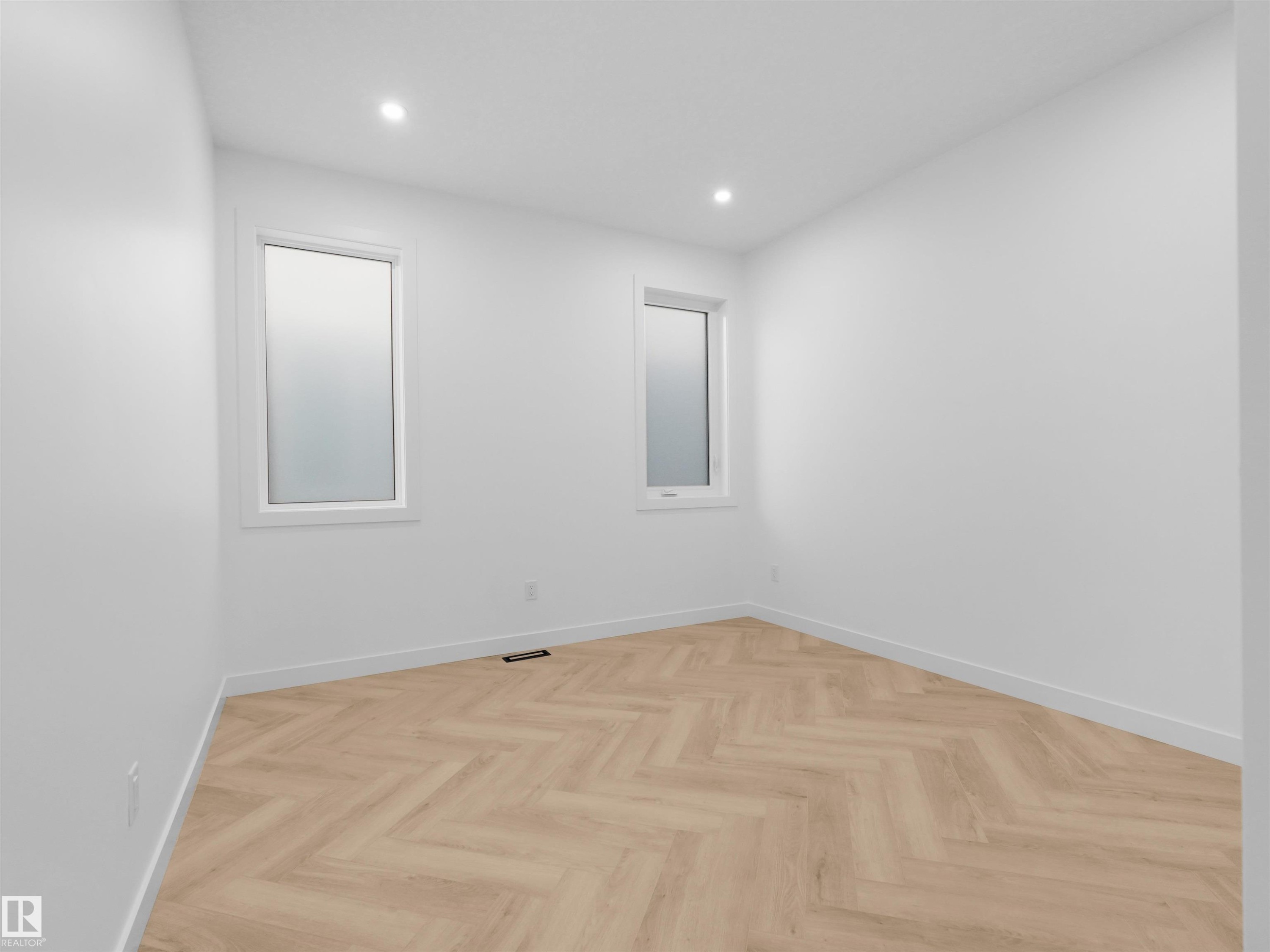 Bright bedroom featuring two windows, recessed lighting, white walls, and wood-finish flooring in a herringbone pattern - 2070 Collip Crescent Sw, Edmonton, AB - Indoor Photo Showing Other Room