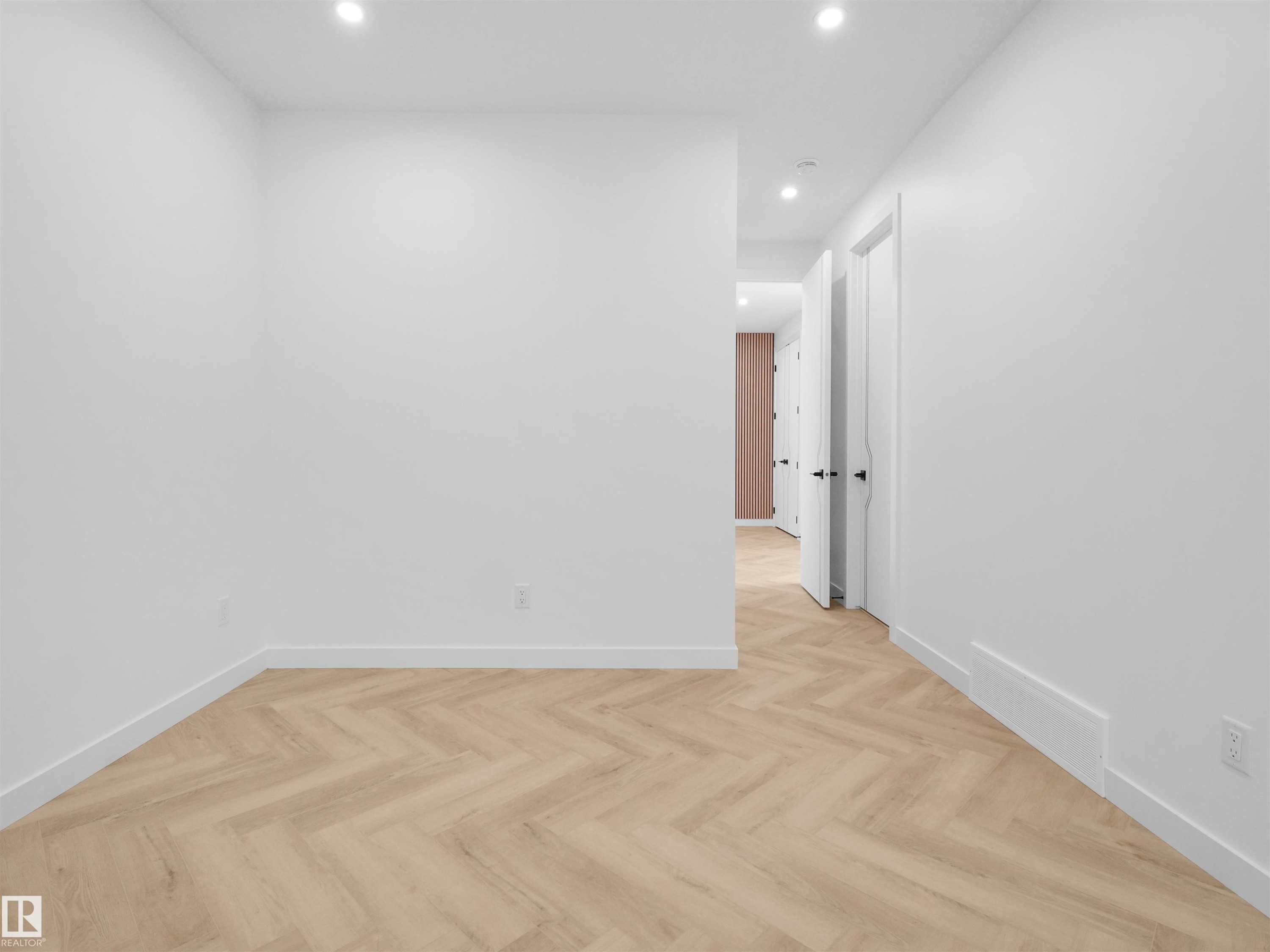Bright bedroom featuring recessed lighting, wood-finish flooring with a herringbone pattern, white baseboards, and white walls - 2070 Collip Crescent Sw, Edmonton, AB - Indoor Photo Showing Other Room