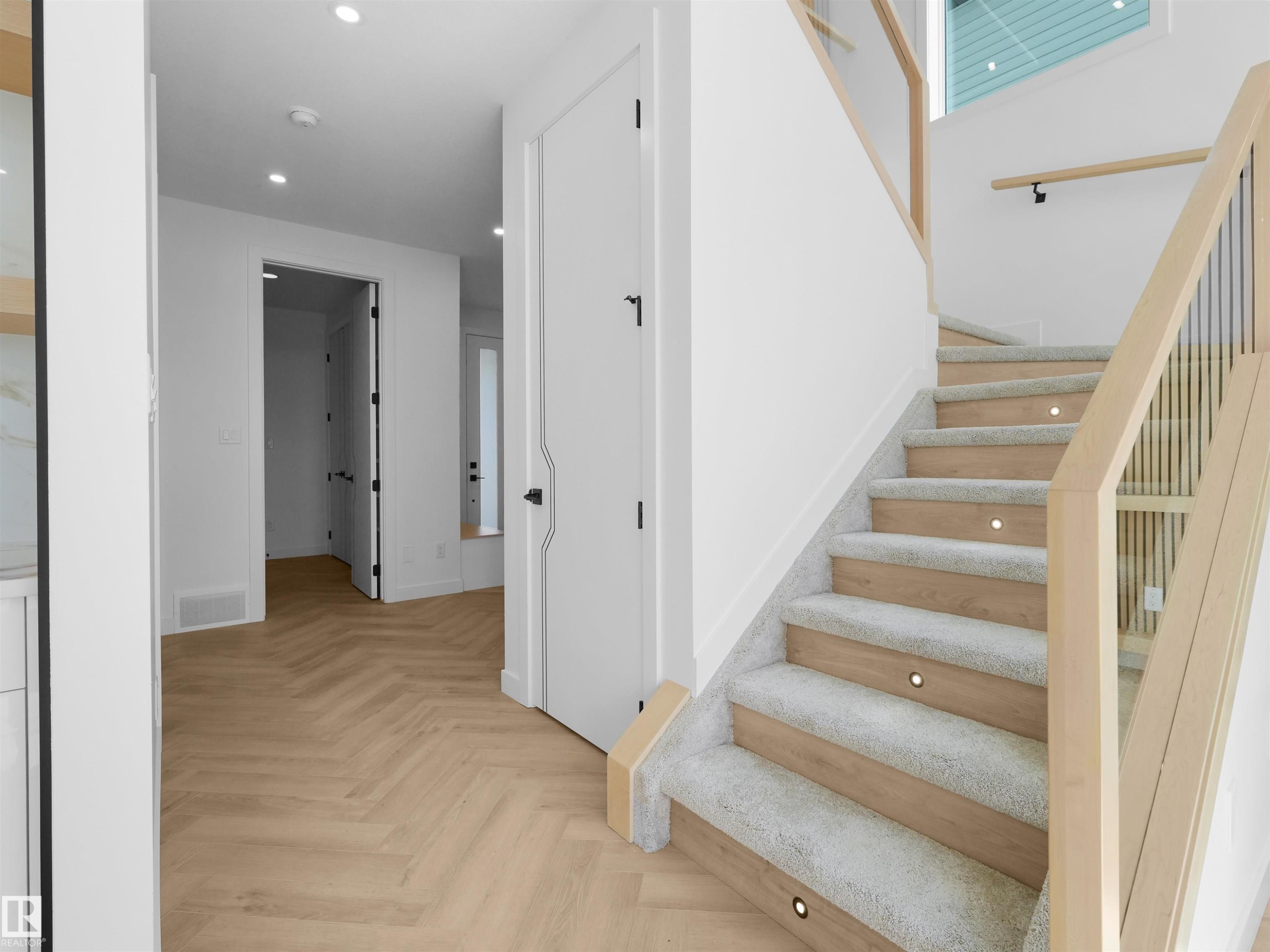 Staircase featuring wood-finish treads with carpet runners, integrated step lighting, and a contemporary wood and metal railing - 2070 Collip Crescent Sw, Edmonton, AB - Indoor Photo Showing Other Room